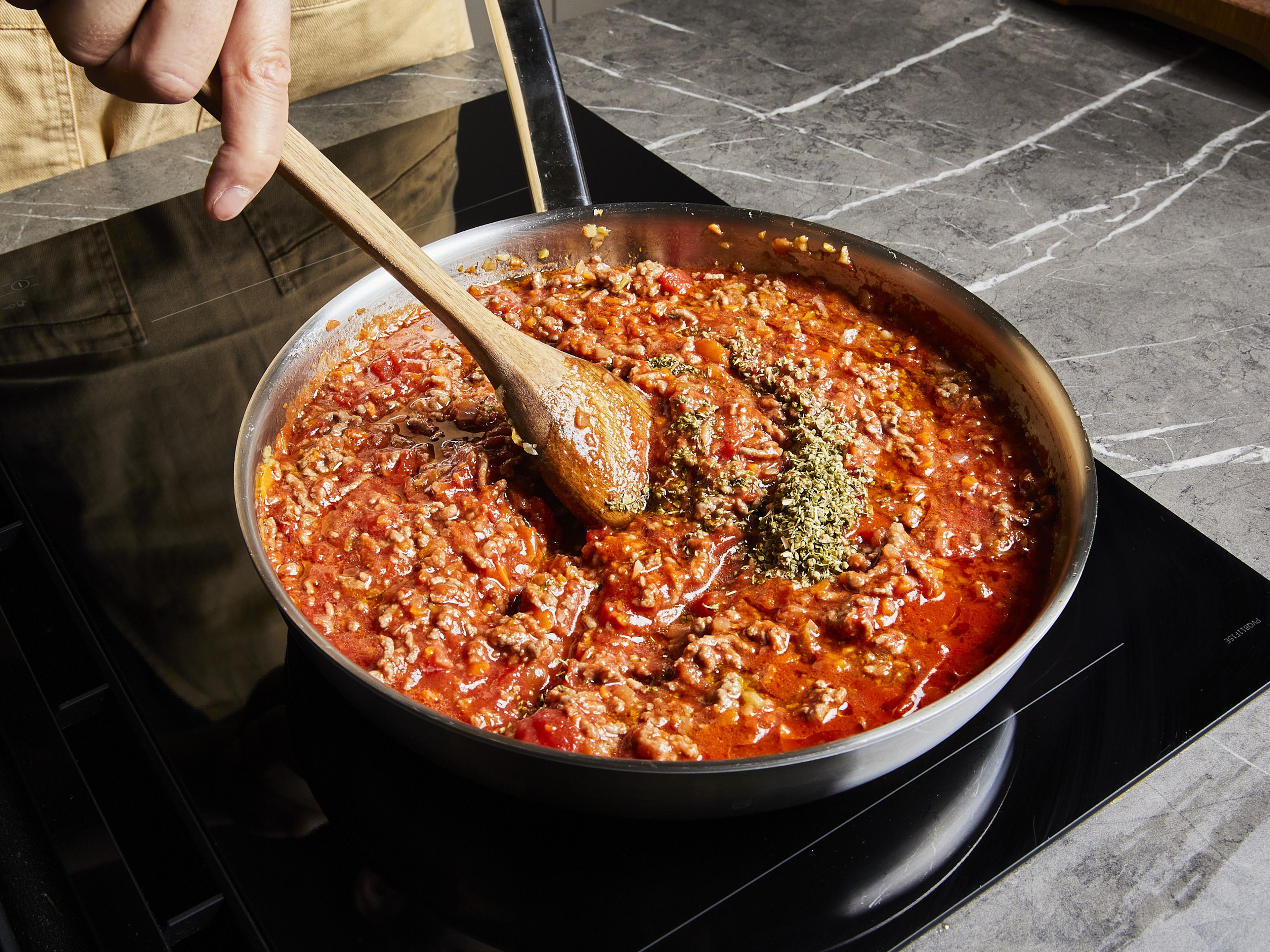 Die stückigen Tomaten aus der Dose, Tomatenmark, Salz, Pfeffer und getrockneten Oregano hinzufügen. Unbedeckt bei mittlerer Hitze ca. 15–30 Min. köcheln lassen, bis die Soße eingedickt ist.