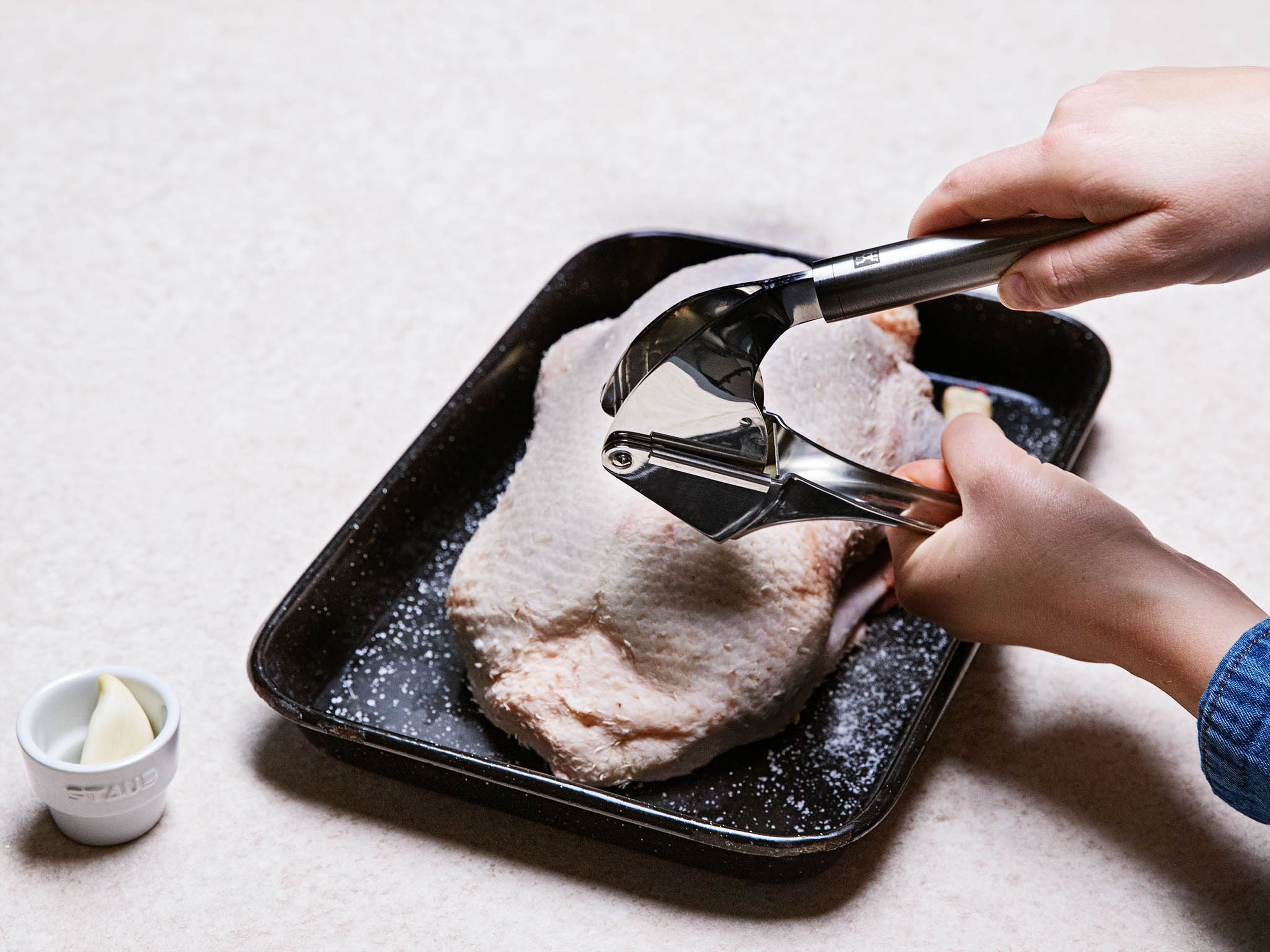 Den Ofen auf 180°C vorheizen. Die Ente trocken tupfen und ggf. Flügelenden und Sterz entfernen. Den Knoblauch pressen. Die Ente von allen Seiten salzen und mit Knoblauch einreiben.