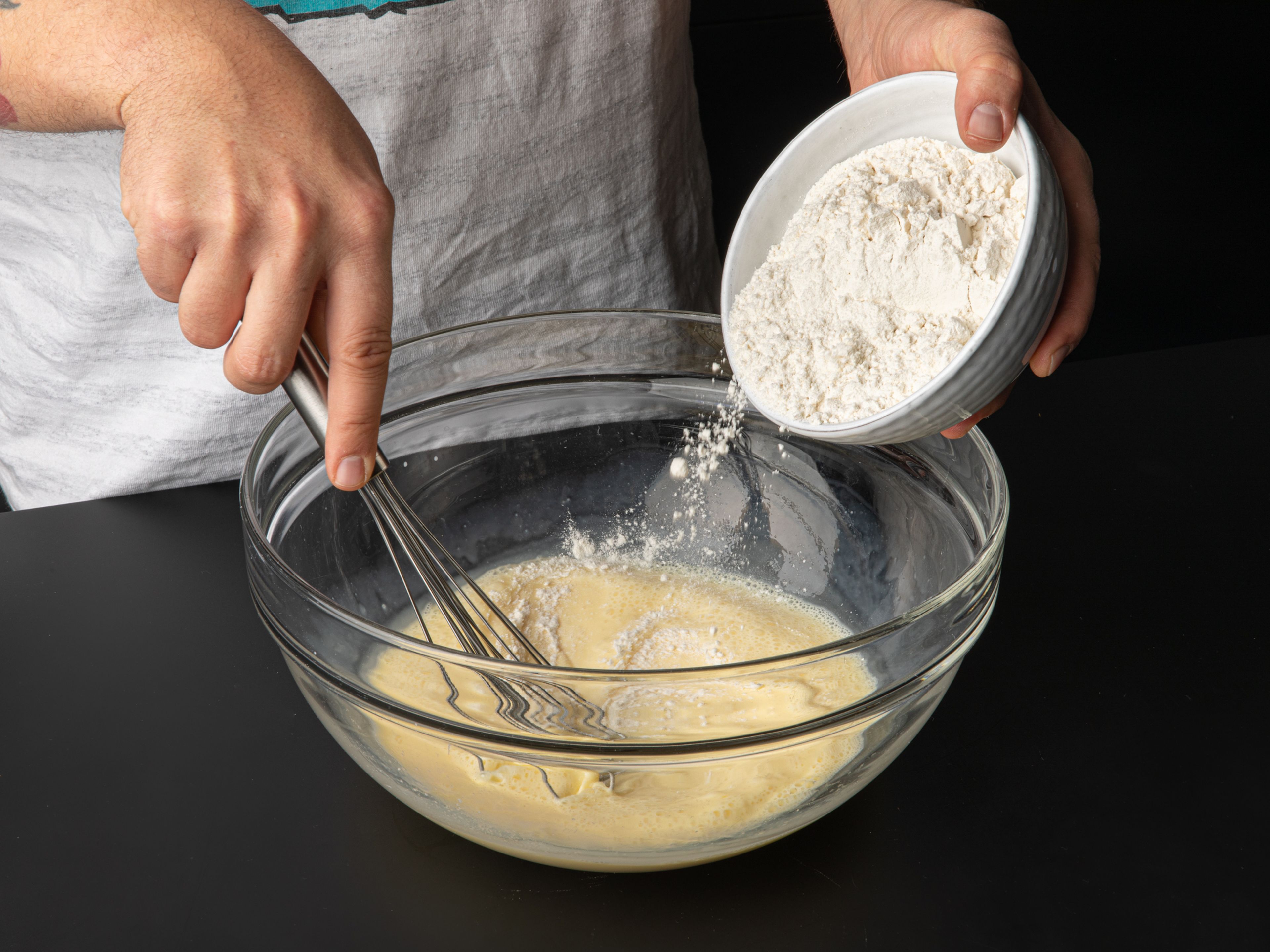 Eier, Milch, Sprudelwasser, Zucker und eine Prise Salz in einer großen Schüssel verquirlen. Nach und nach das Mehl klümpchenfrei untermischen. Wenn du etwas Zeit hast, den Teig abdecken und ca. 30 Min. ruhen lassen, oder direkt mit Schritt 2 fortfahren.