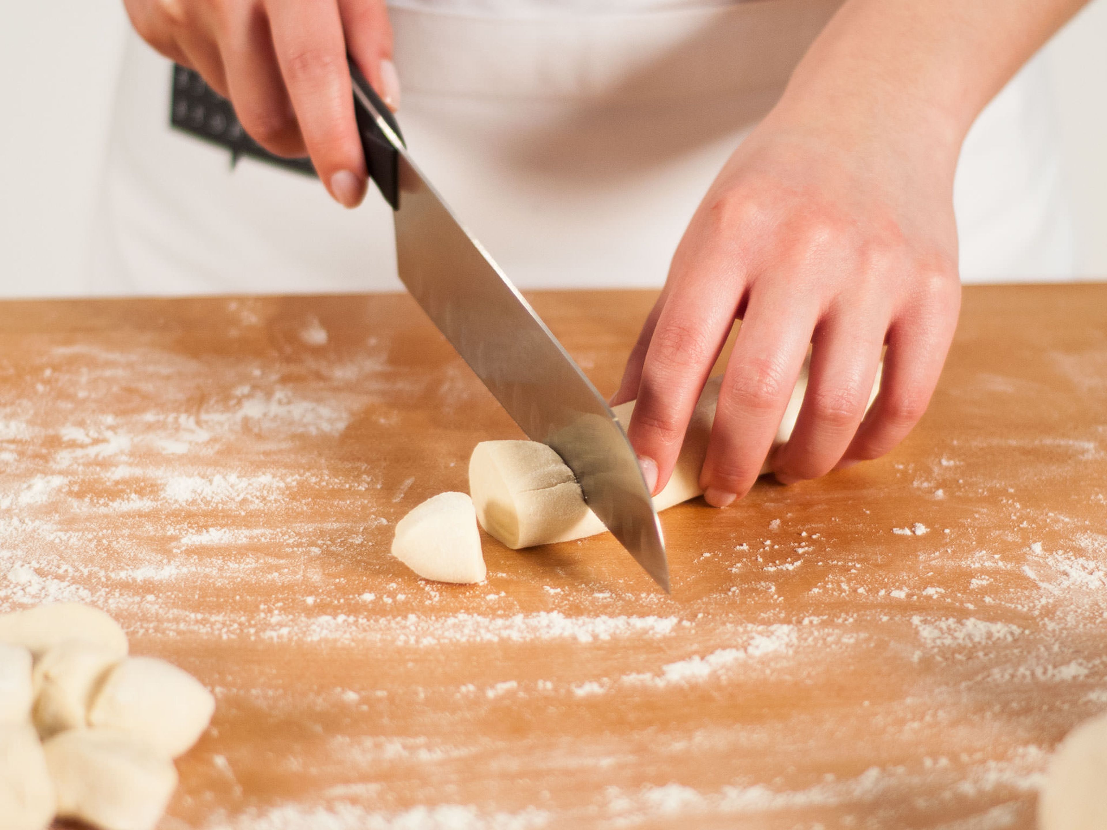 On a lightly floured work surface, knead the dough. Using a sharp knife, separate into 4 equally sized portions. Halve quarters and roll each portion into a small log. Cut each log into 8 walnut-sized pieces.