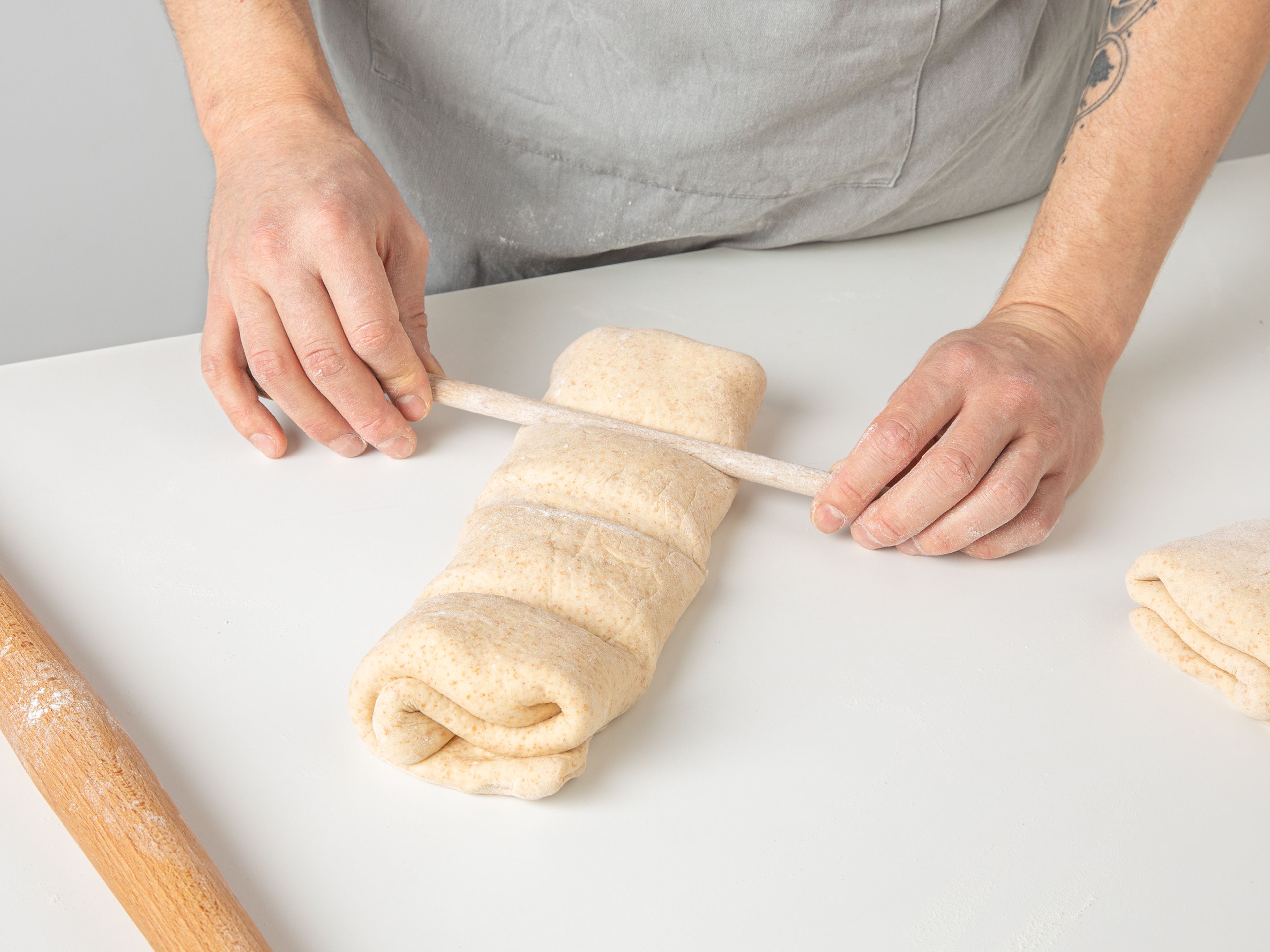 Use the handle of a wooden spoon to press down the dough while not cutting all the way through it, to create four lines on the bread roll. This will divide the bread into four equal pieces and make it easier to portion after baking. Make a shallow diagonal slice on each piece with a small knife. Place the bread rolls on a baking sheet lined with parchment paper. Bake in the preheated oven for approx. 15 min., or until lightly browned on top. Remove the bread from the oven and divide it into portions. Top with a dollop of sour cream and sprinkle with remaining chopped chives. Serve while still warm!