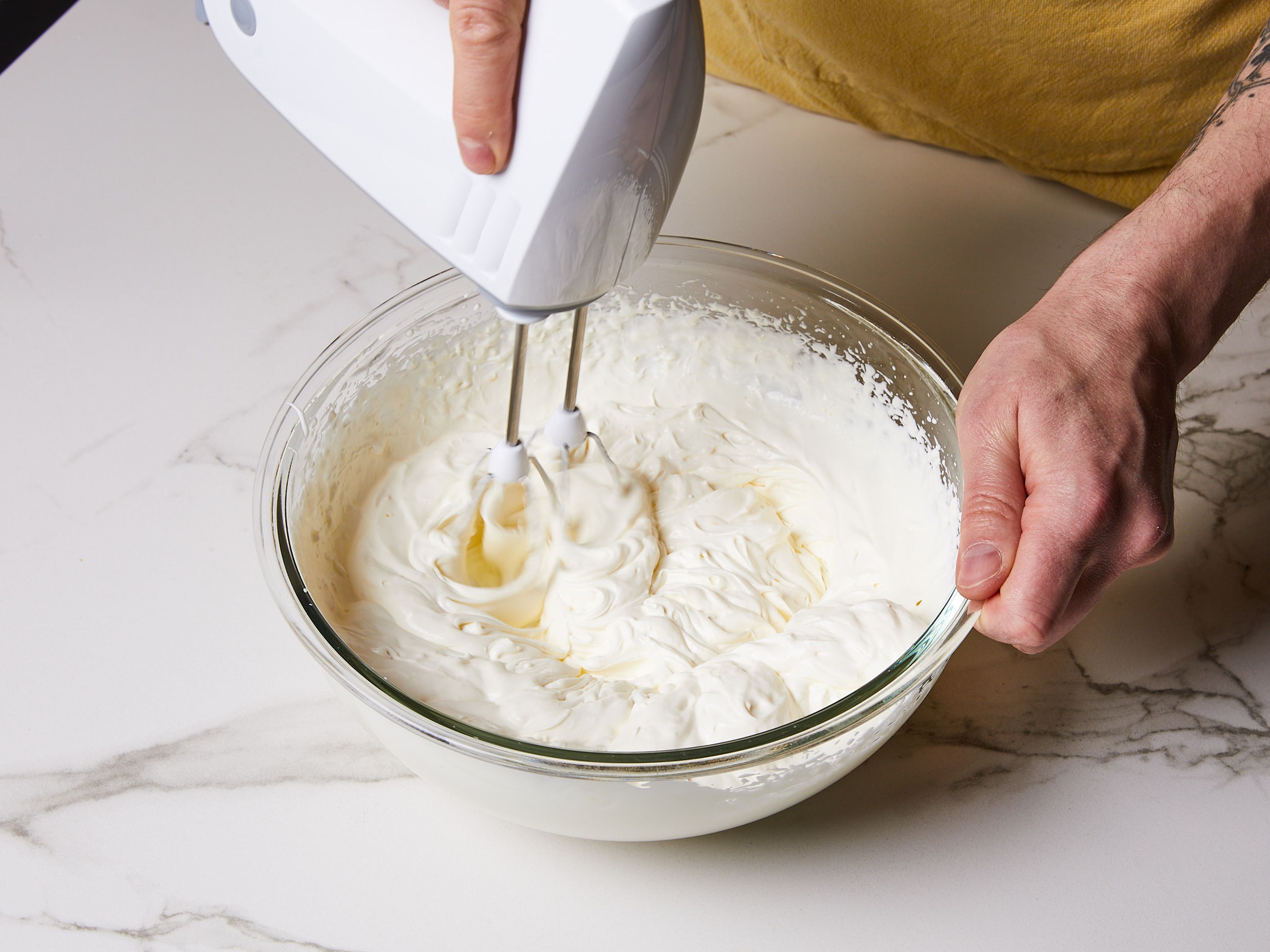 Next, finely grate the lemon zest. For the mascarpone cream, in a large bowl, combine mascarpone, lemon zest, sugar, and heavy cream. Whip until stiff and fluffy with a hand mixer.