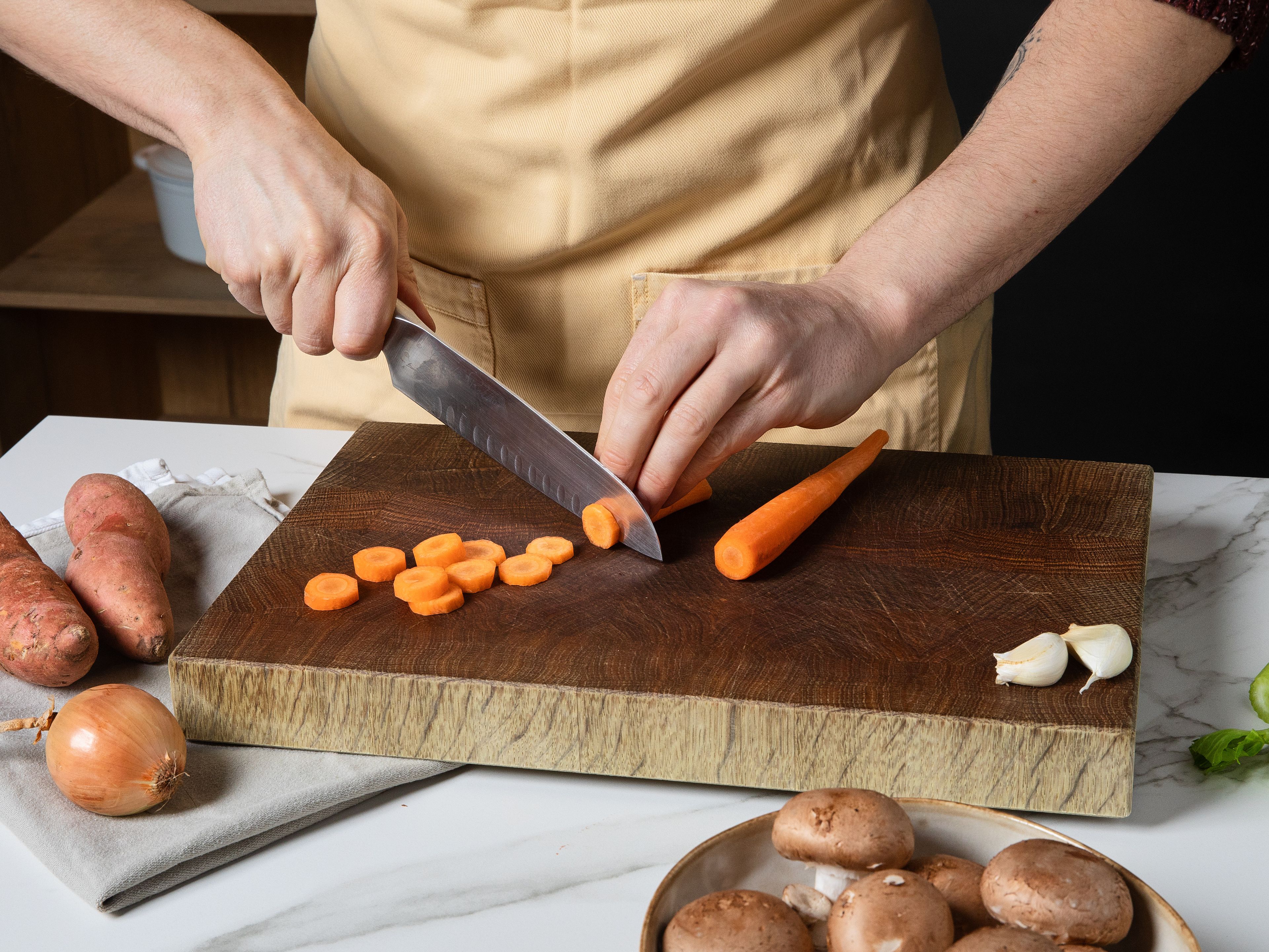 Wildreis nach Packungsanleitung kochen, abgießen und beiseite stellen. Die Zwiebeln und Süßkartoffeln würfeln, den Knoblauch hacken. Die Karotten würfeln, die Selleriestangen und Champignons in Scheiben schneiden. In einem großen Topf Öl erhitzen. Darin Zwiebeln, Knoblauch, Karotten, Sellerie und Champignons ca. 5 Min. anbraten, bis sie leicht gebräunt sind.