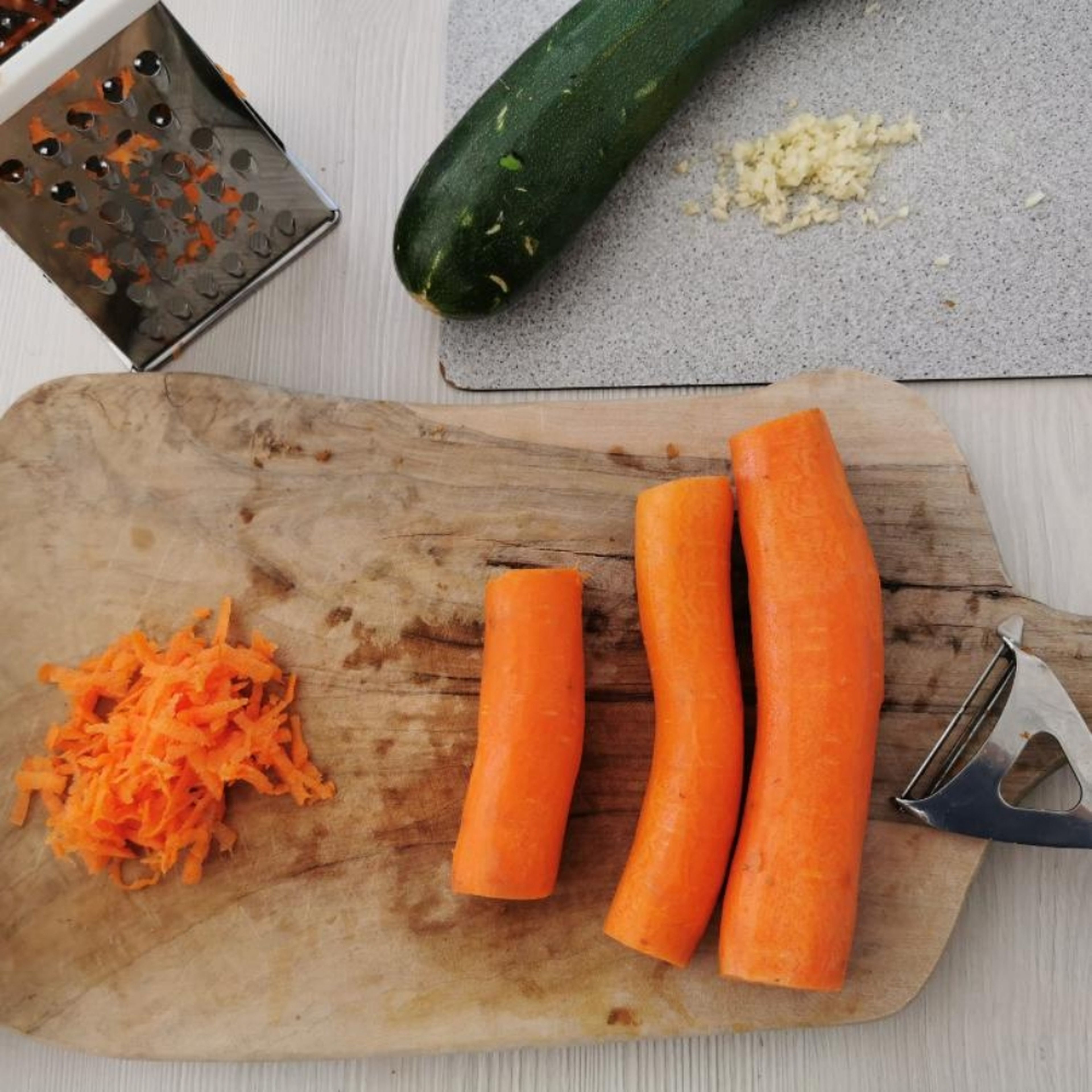 Zunächst Knoblauch abziehen und fein hacken. Karotten schälen und raspeln. Zucchini in kleine Würfel schneiden. Koriander fein hacken