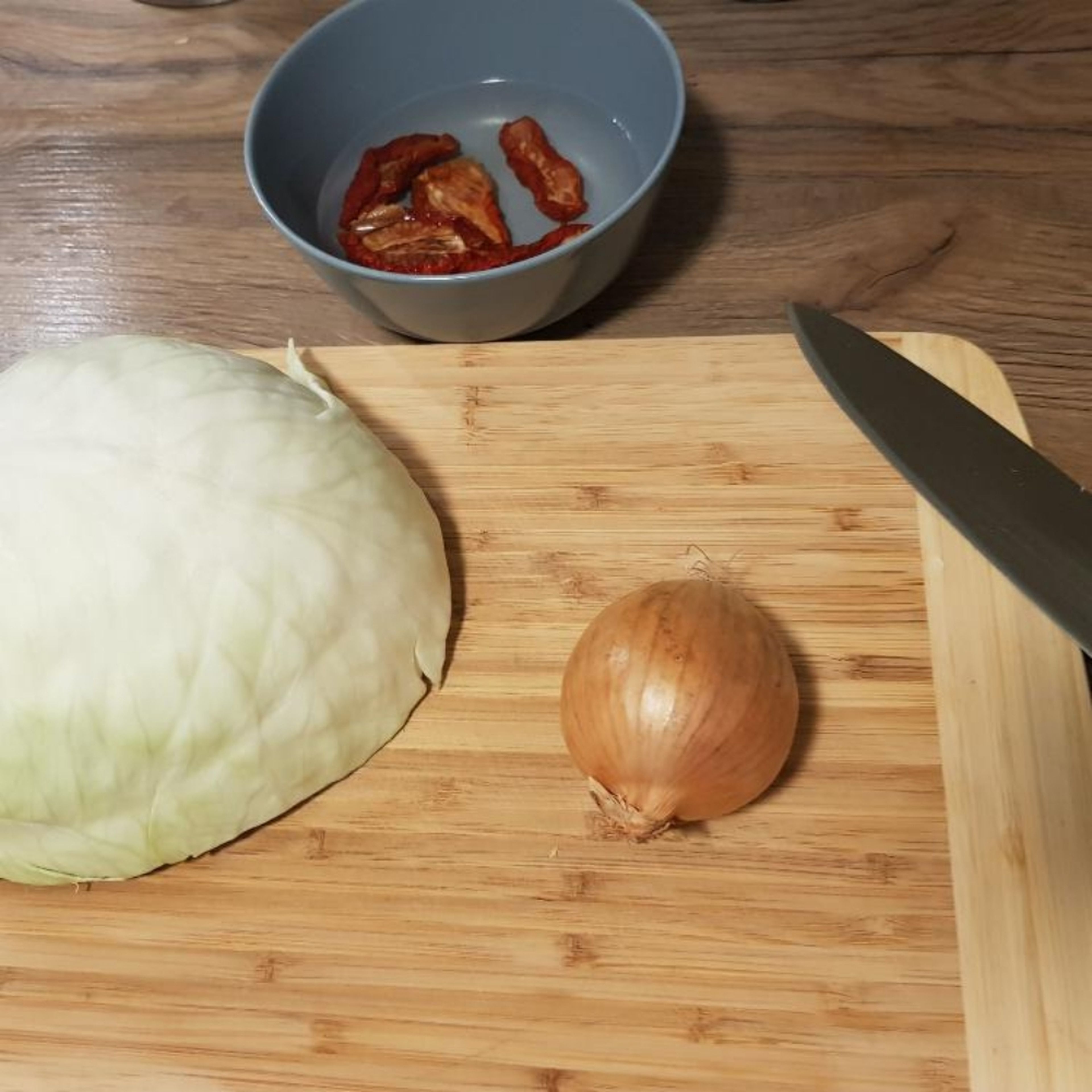 Kohl in Streifen schneiden. Zwiebeln fein würfeln. Geteocknete Tomaten in einer kleinen Schüssel separat mit heißem Wasser übergießen und quellen lassen.