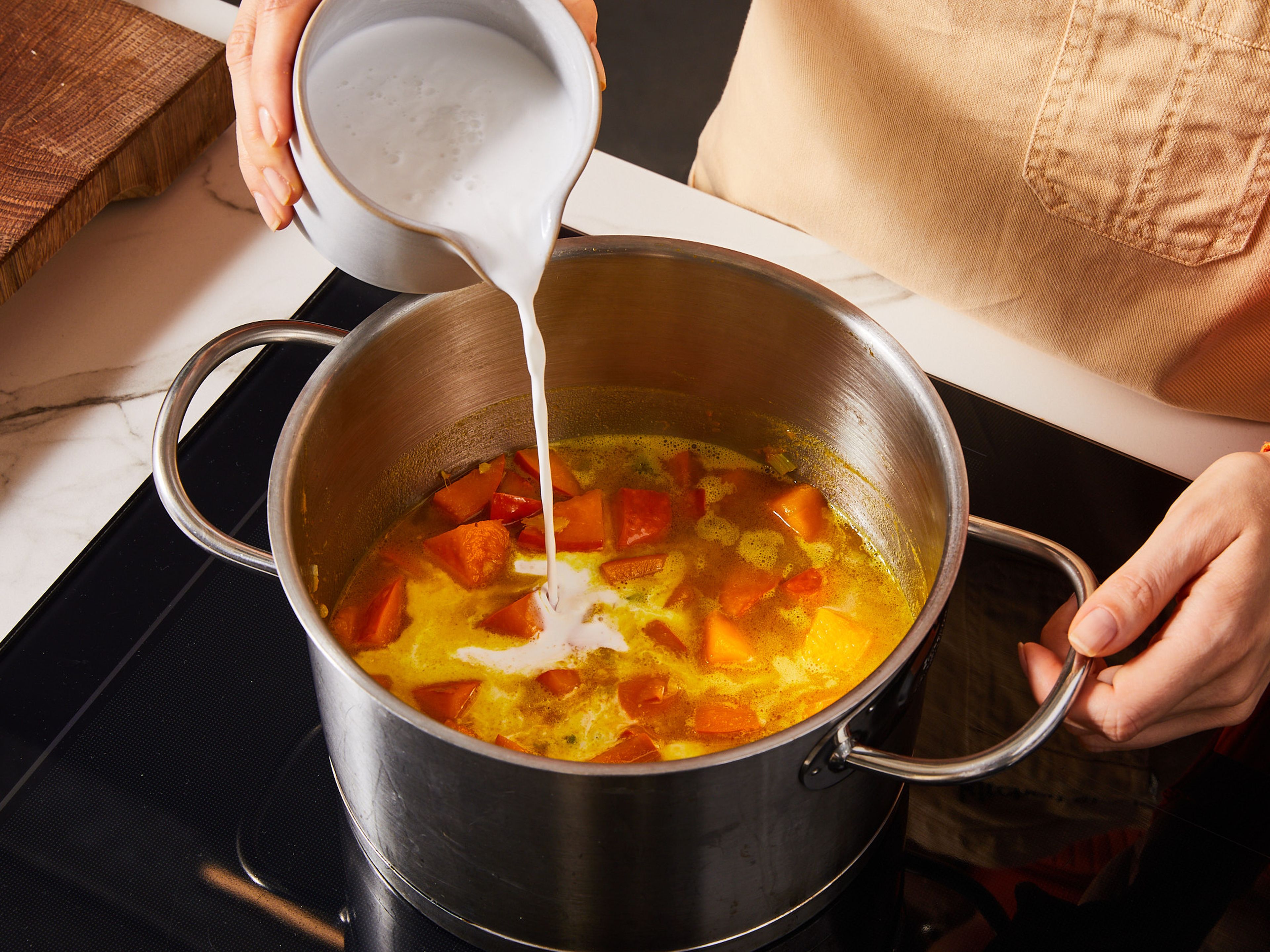 Öl in einem mittelgroßen Topf erhitzen. Ingwer, Knoblauch und den weißen Teil der Frühlingszwiebeln hinzufügen und glasig dünsten. Den Kürbis hinzufügen und ca. 5 Min. braten. Currypulver zugeben und kurz mitbraten und zuletzt mit Gemüsebrühe und Kokosmilch ablöschen. Weitere 7 Min. köcheln lassen, bis der Kürbis weich ist.