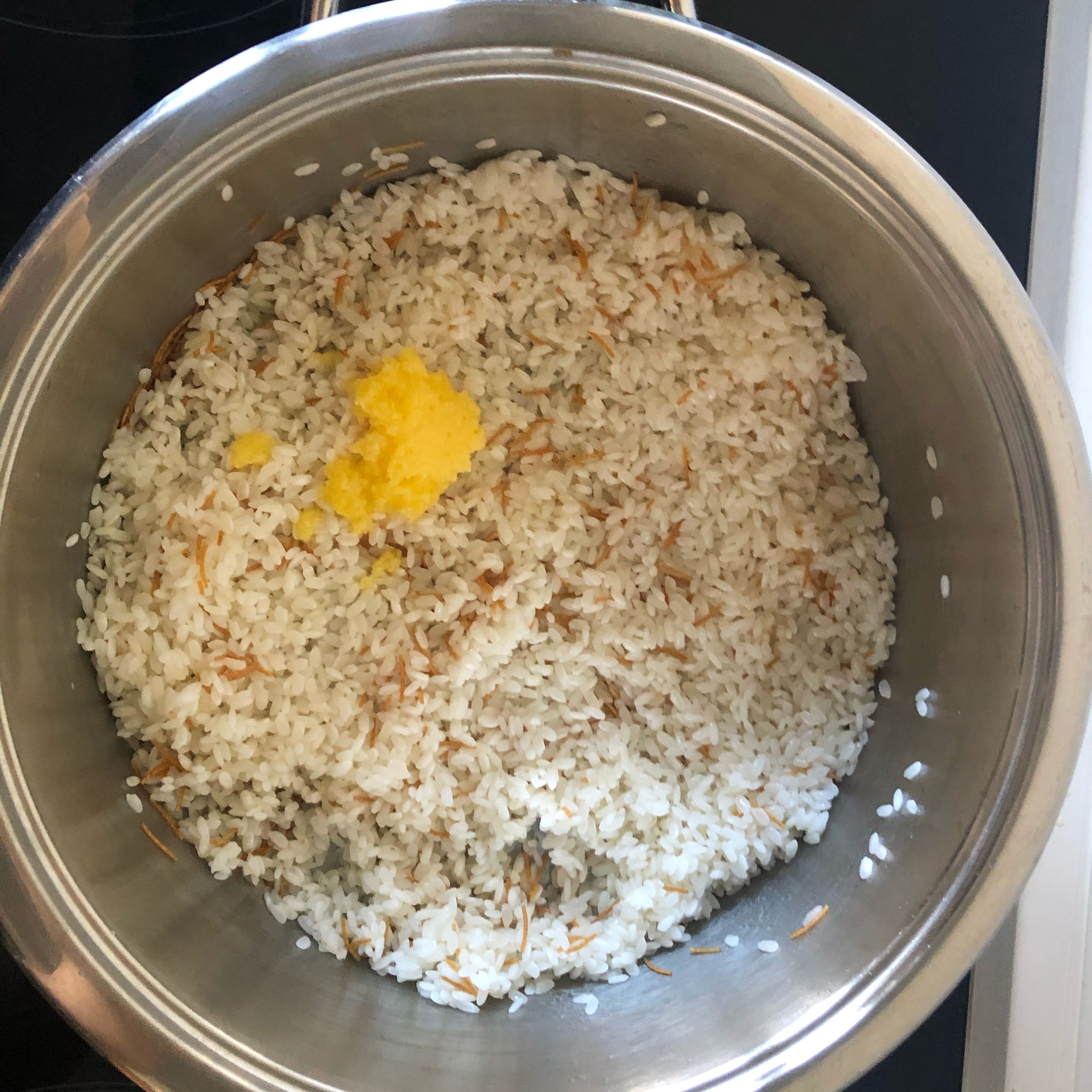 Den abgetropften Reis in den Topf geben, vermischen und dann die Butter hinzufügen (alles gut vermischen. Und kurz unter ständigem Rühren braten lassen).