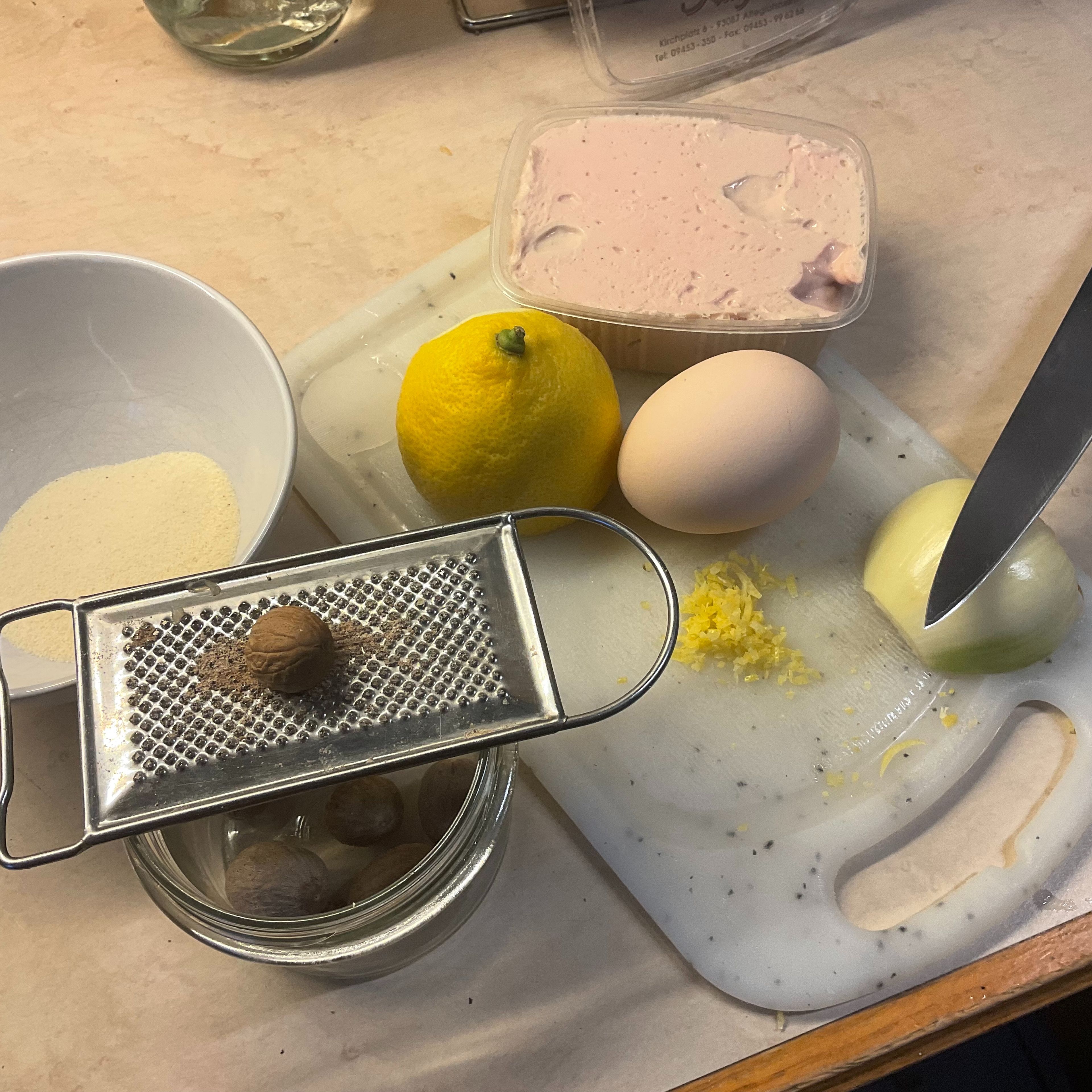 Dann richte ich alles für die Brätknödel her. Das Kalbsbrät, ca 2 Schnitzer unbehandelte Zitronenzeste feinst geschnitten, bzw. Zitronenabrieb, ein Ei, eine halbe Zwiebel, Muskatnuss mit Reibe und ca. 15 g feinen Gries.