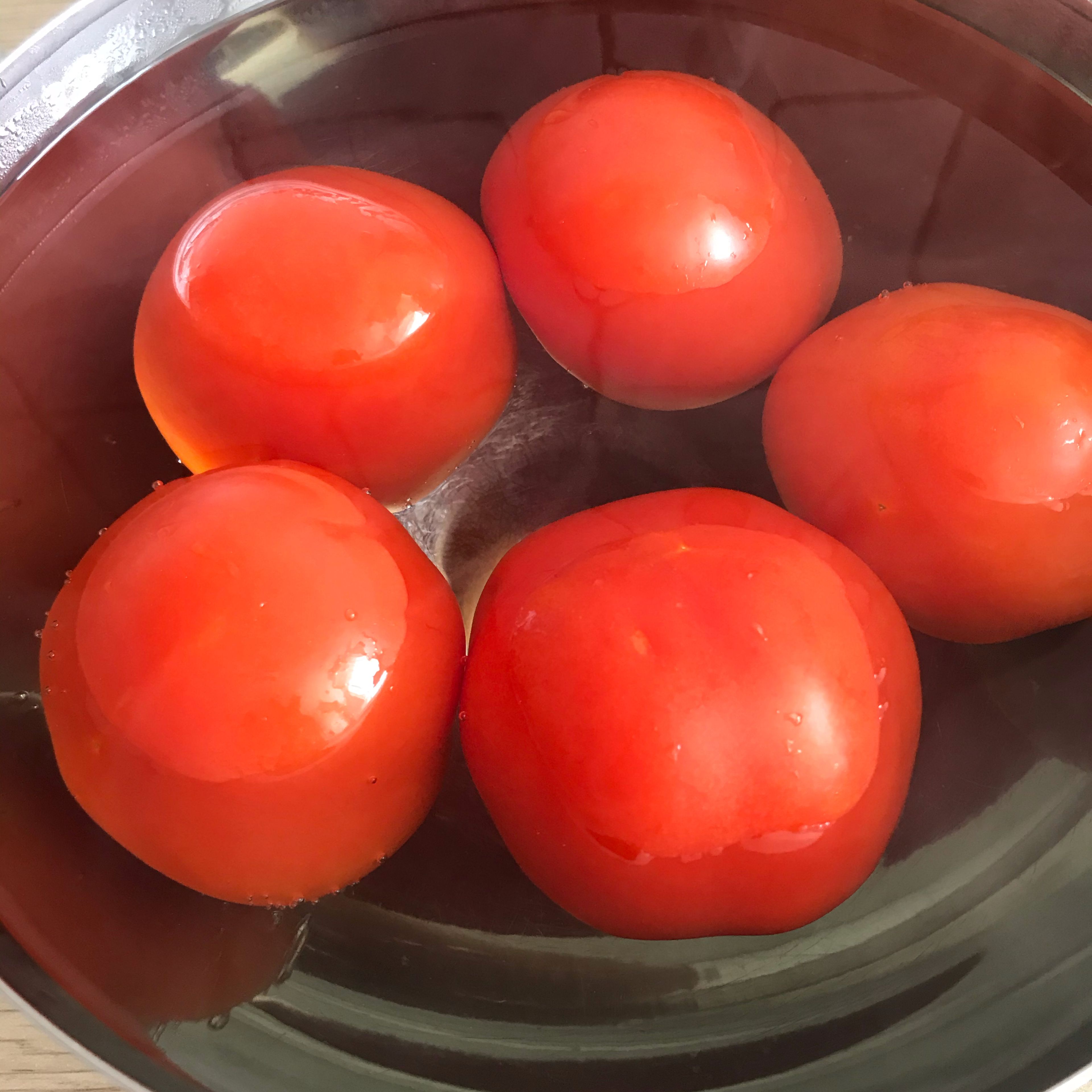 Das Gemüse im Öl bei geschlossenem Deckel ohne Messbecher andünsten (3D-Rührer | Stufe 1| 130°C | 4 Min.). Währenddessen die Tomaten in eine Schüssel geben und mit gekochtem Wasser begießen.