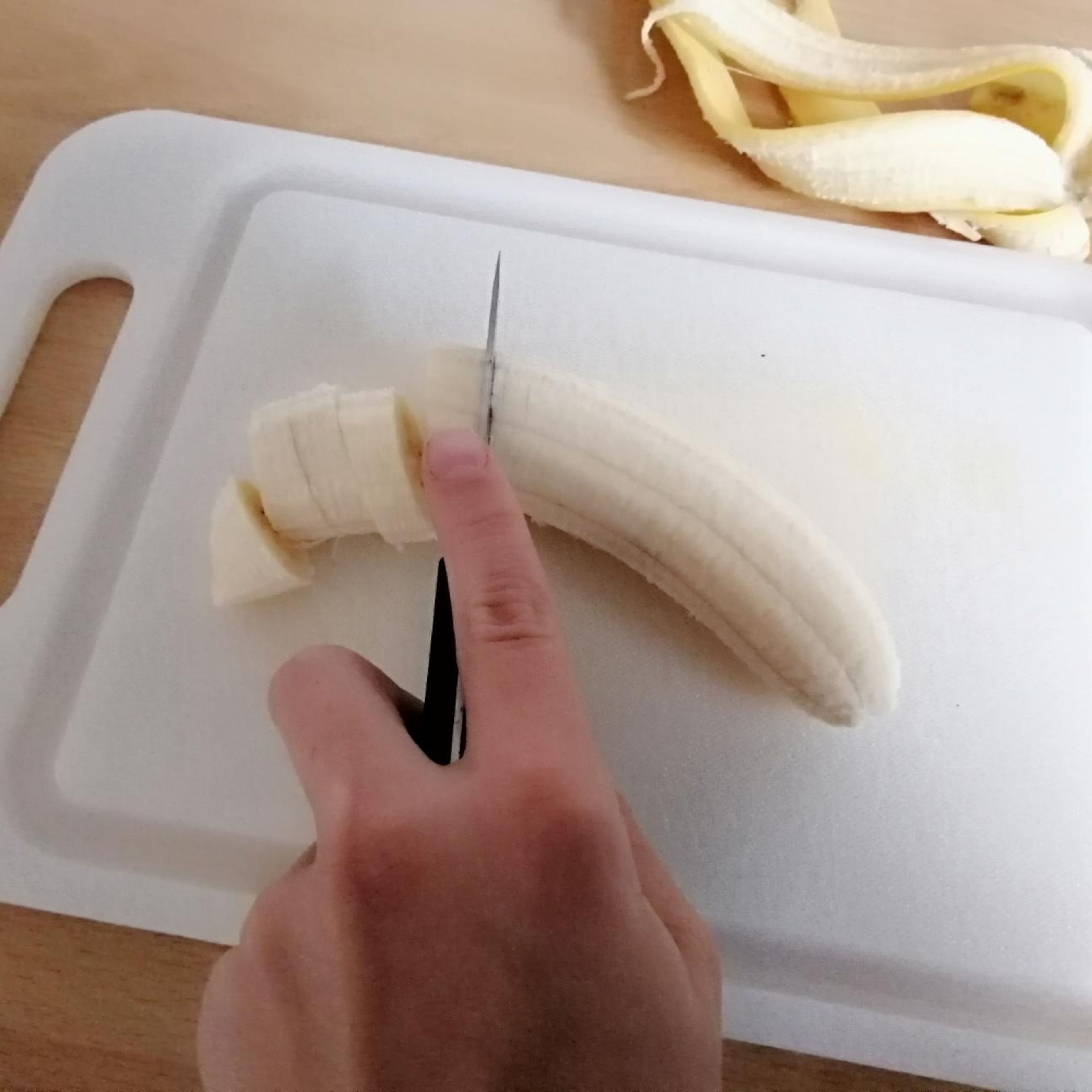 Bananen mit einem Messer in dünne Stücke schneiden