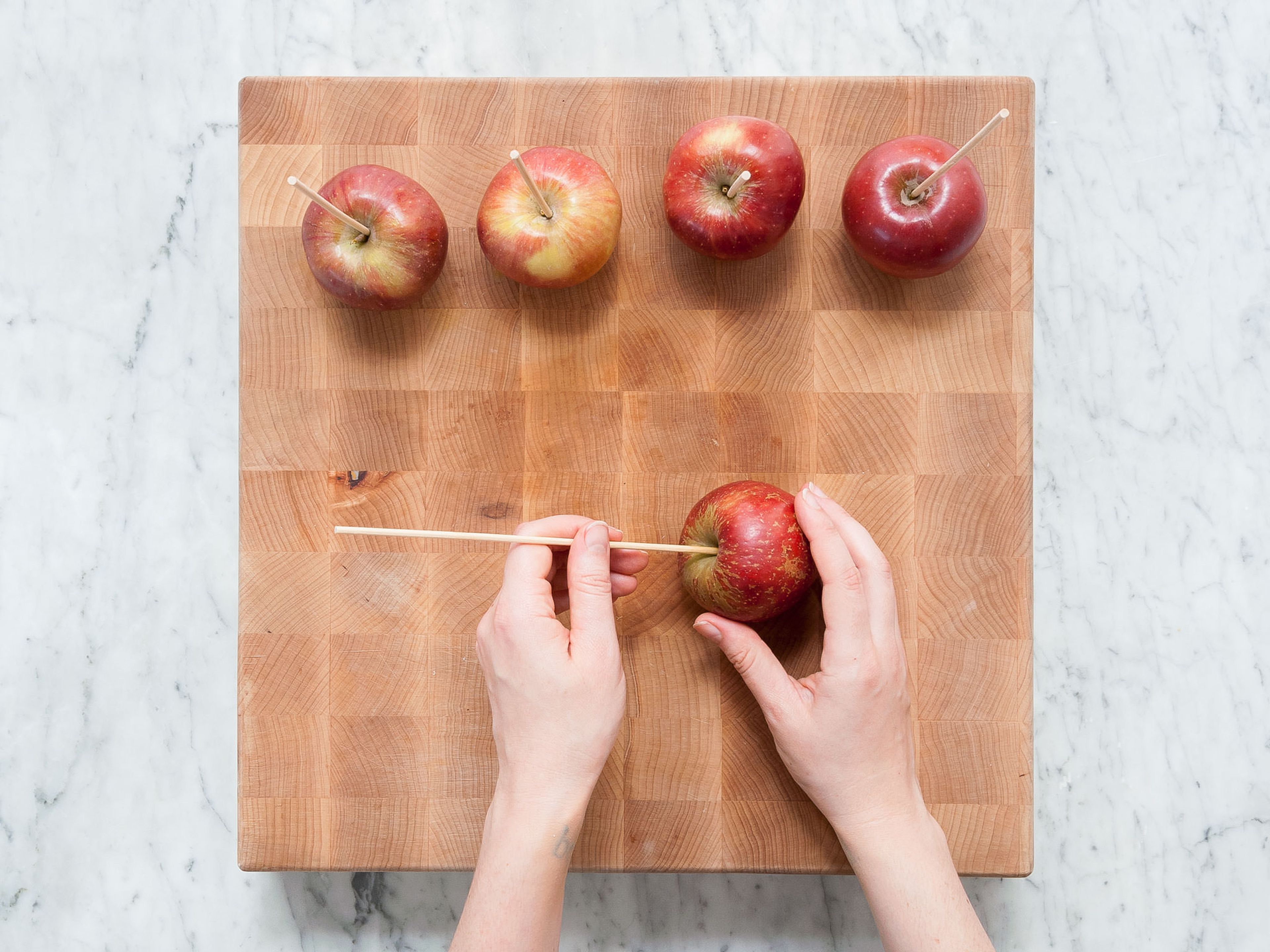 Äpfel waschen und den Stiel entfernen. Je einen Holzspieß in das Stielende eines Apfels stechen. Beiseitestellen.