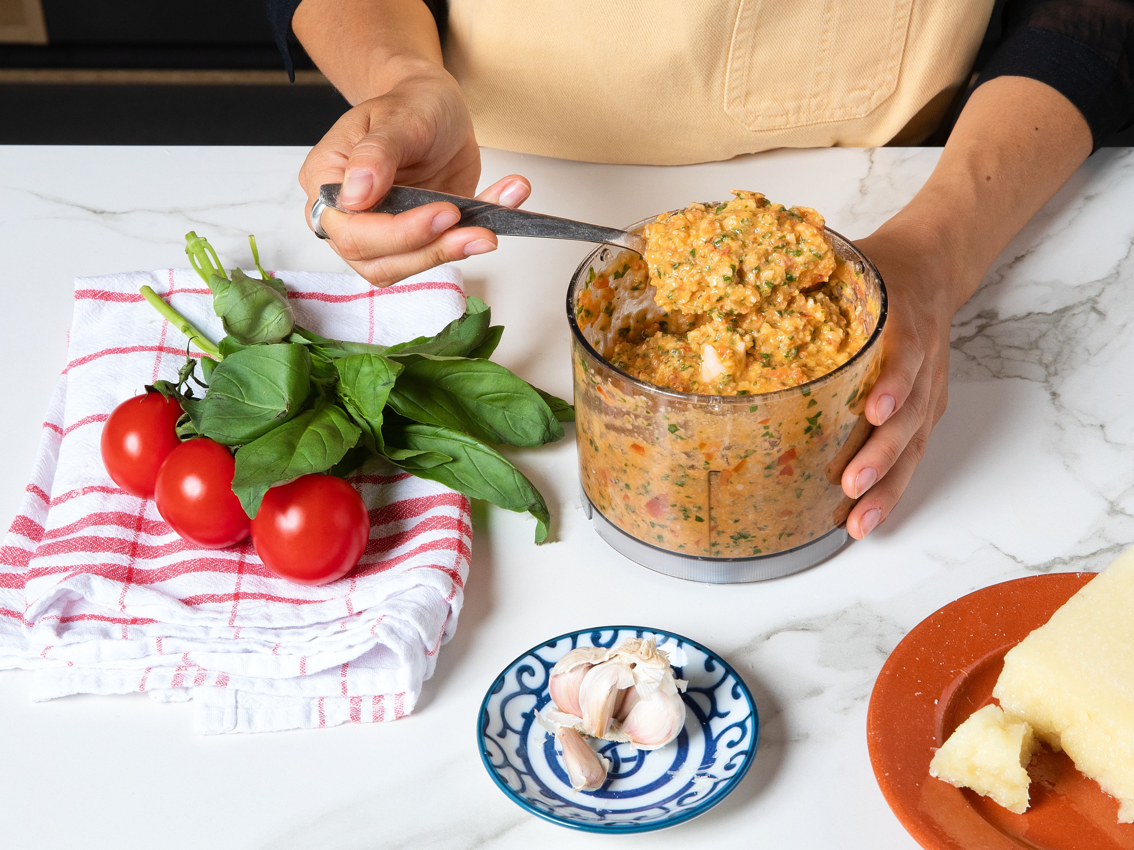 Halve the tomatoes. Lightly crush and peel the garlic cloves and set one aside for later. Pick the basil leaves and finely chop the parsley. For the pesto, blend almonds, garlic, basil, and tomatoes with olive oil and grated cheese in a food processor until a coarse, slightly chunky paste forms. Season with salt and pepper. Alternatively, use a mortar and pestle: first crush the almonds and garlic until coarse. Add the basil and work it in, then crush the tomatoes. Stir in the olive oil and grated cheese and season with salt and pepper. Cover and let sit for a few minutes before serving.
