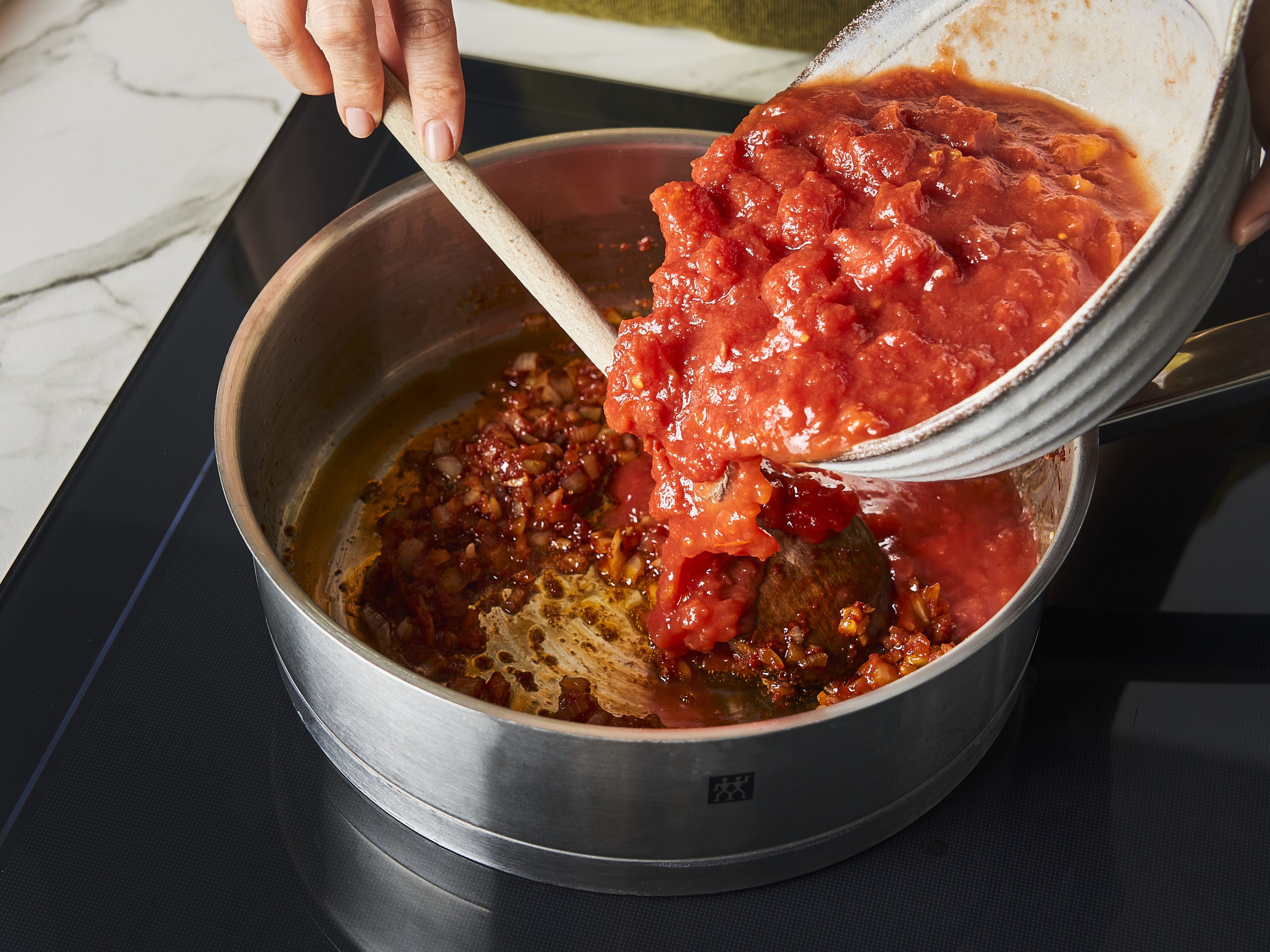 Tomaten aus der Dose in den Topf geben und zum Kochen bringen. Salz, Pfeffer, Oregano, Thymian und Rosmarin zur Tomatensoße geben. Für ca. 10–15 Min. köcheln lassen.