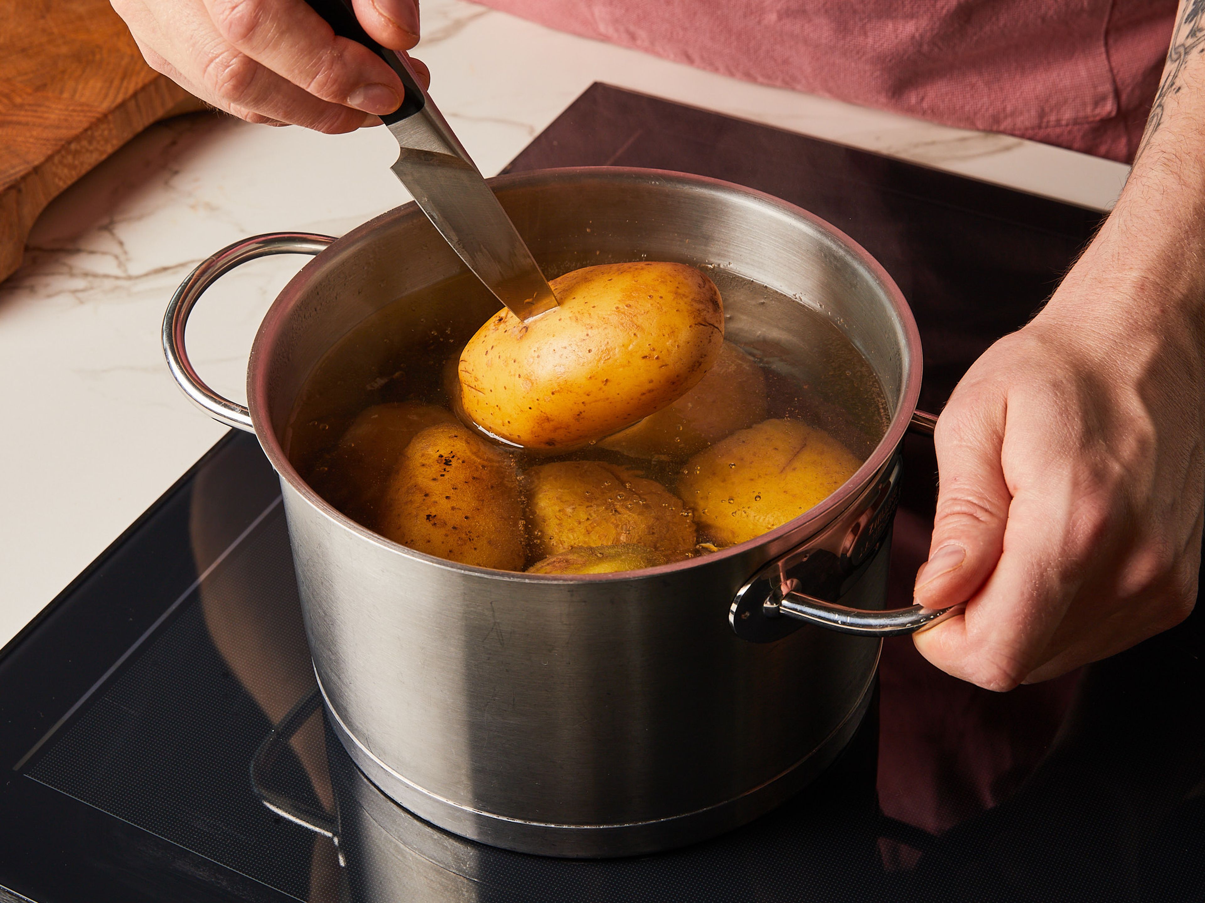 Cook potatoes with skin on in a pot of boiling and salted water and cook for approx. 18–20 min., depending on the potato size, until a fork can poke through with some resistance. Then drain and let the potatoes cool down.
