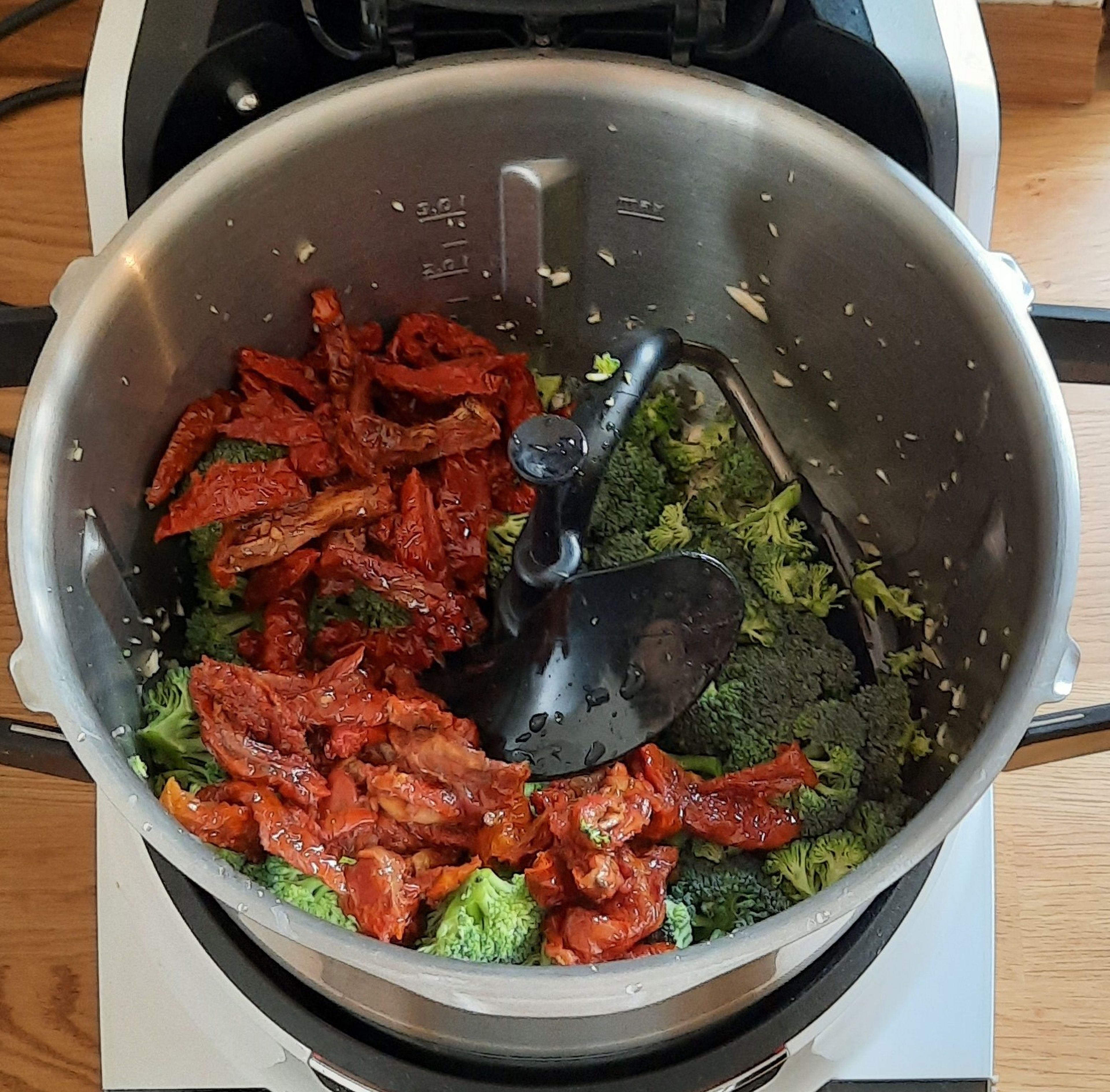 3D-Rührer einsetzen. Brokkoli in kleine Röschen schneiden. Die getrockneten Tomaten abgießen, dabei aber das Öl auffangen. Die Tomaten dann in Streifen schneiden. Das Öl der Tomaten in den Cookit einwiegen (ca. 60 g). Brokkoli und die geschnittenen Tomaten dazugeben. Alles bei geschlossenem Deckel, ohne Messbecher, anbraten (3D-Rührer | Stufe 2 | 140°C |  3 Minuten).