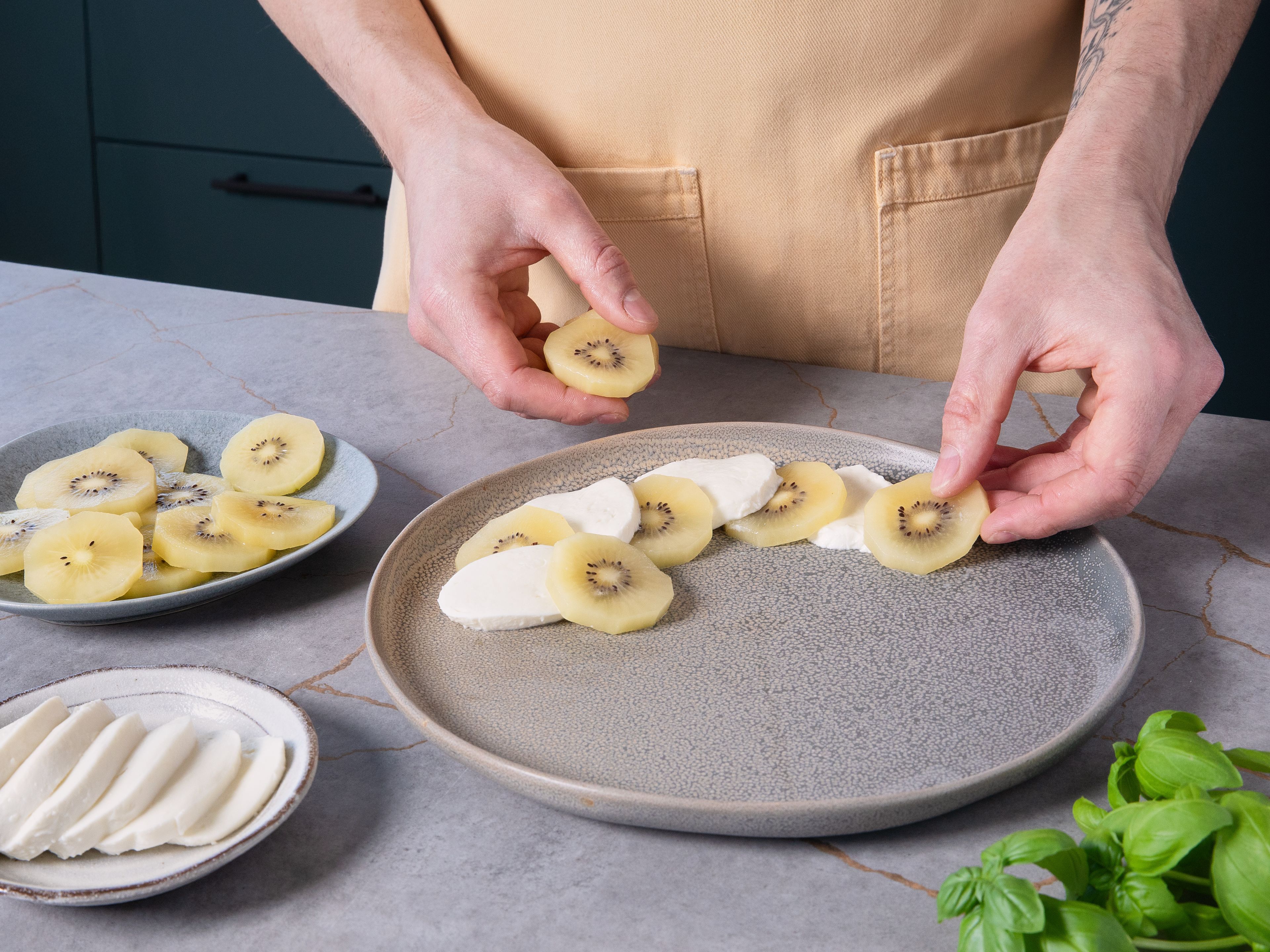 Kiwischeiben und Mozzarella abwechselnd auf einer großen Platte anrichten. Mit Olivenöl und Balsamico beträufeln. Zum Schluss mit Zitronensaft, Zitronenabrieb, Salz und Rosa Pfeffer abschmecken. Mit den frischem Basilikumblättern garnieren.