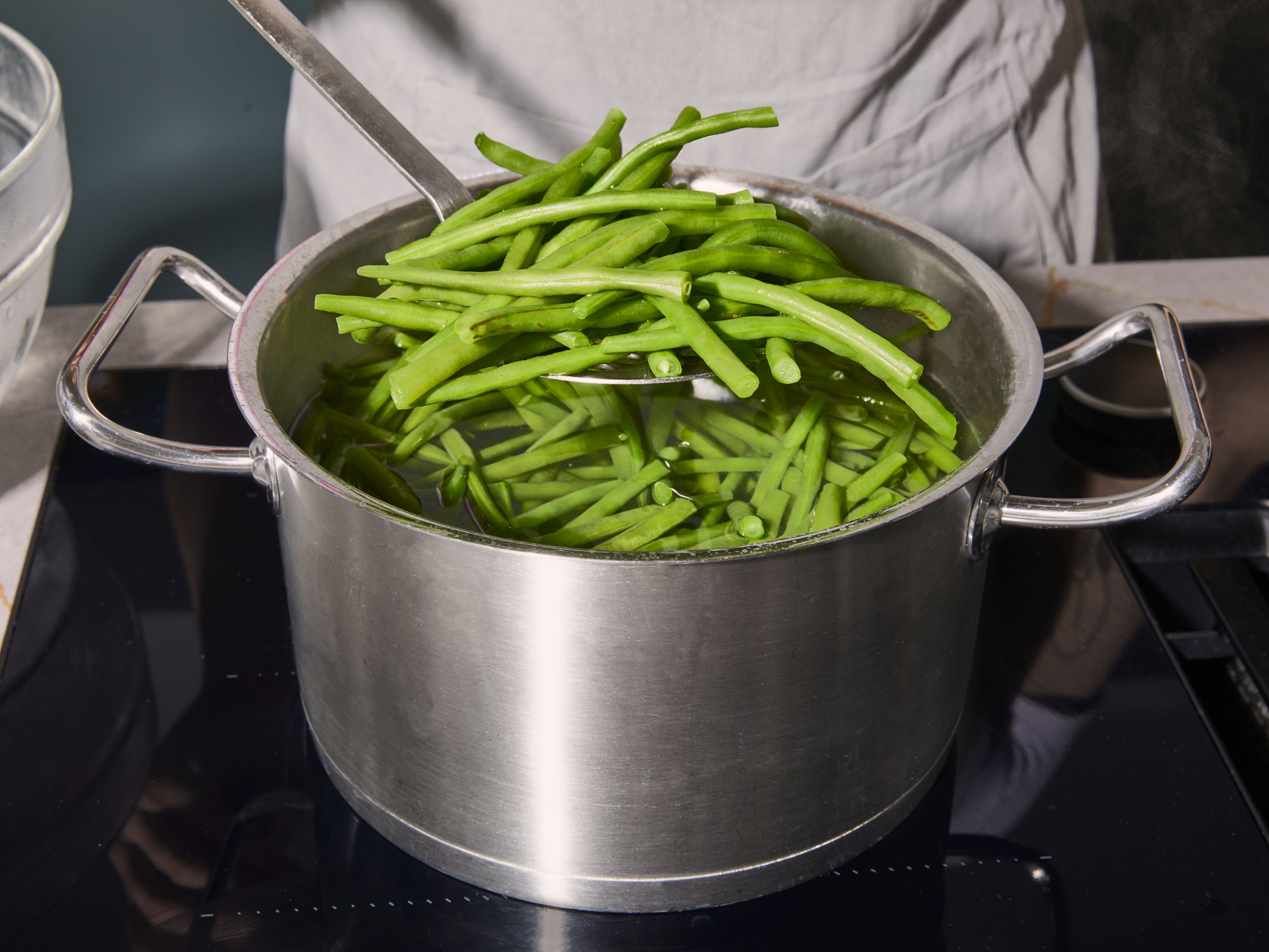 To prepare the green beans, trim the ends off. Bring a large pot of salted water to a boil. Blanch the beans for approx 8–12 min., according to your preferred doneness.