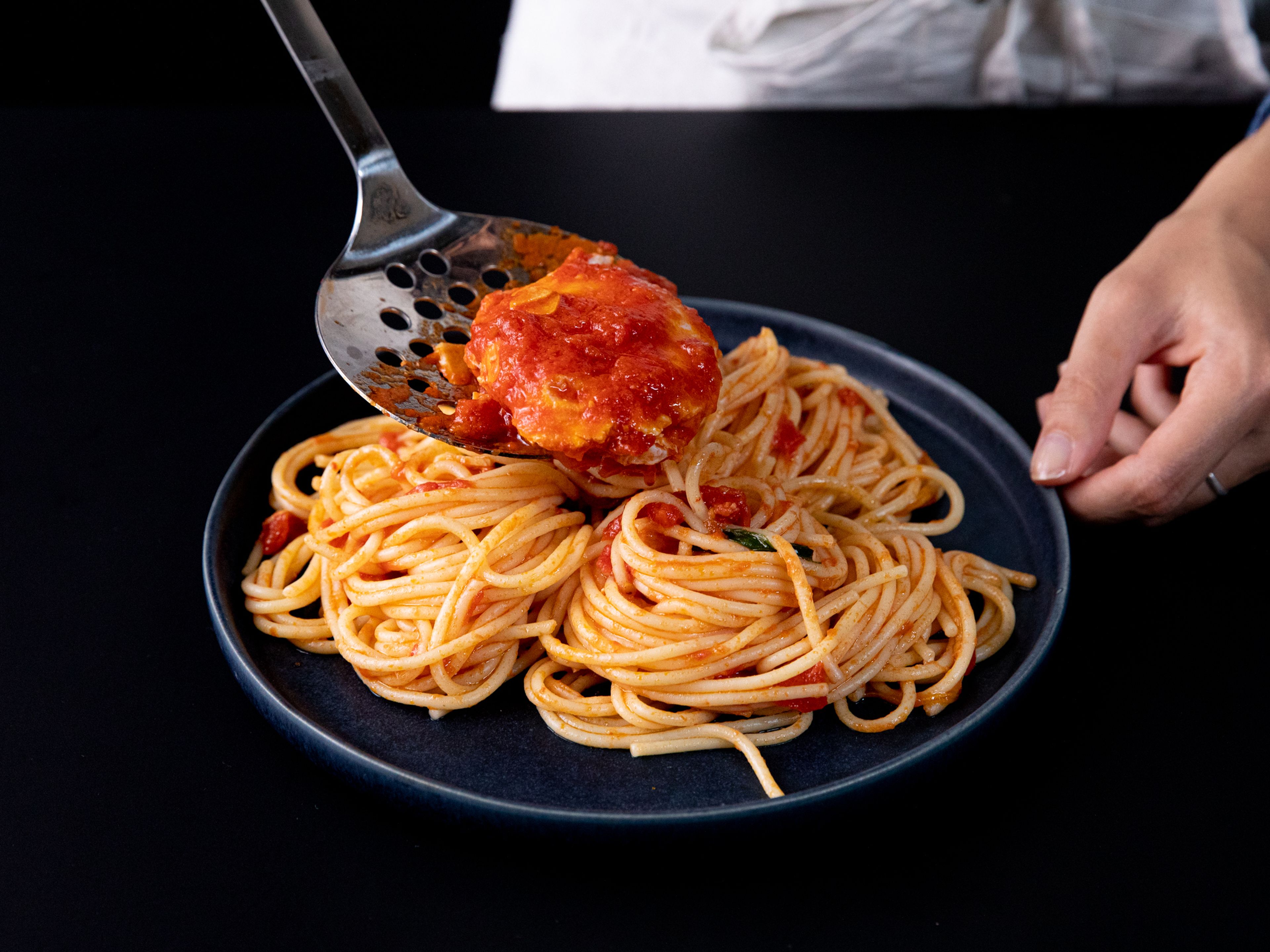 Spaghetti in die Tomatensoße geben und darin schwenken. Dabei so viel Kochwasser der Nudeln wie nötig dazugeben, bis die sämige Soße die Nudeln ummantelt. Auf Servierschüssel aufteilen und jeweils ein pochiertes Ei daraufgeben. Mit geriebenem Parmesankäse bestreuen, falls gewünscht. Guten Appetit!