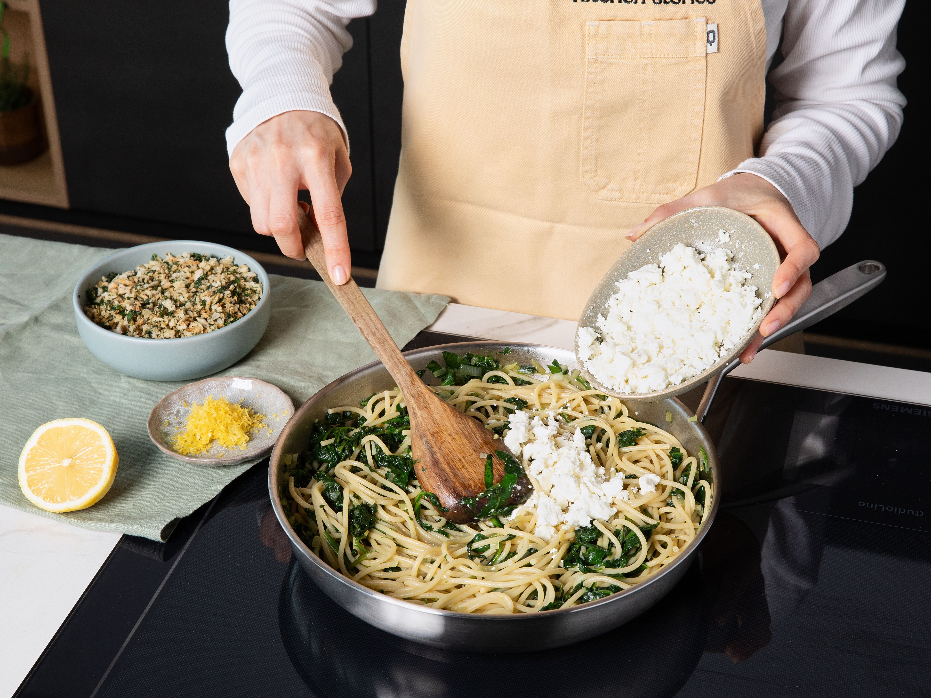 Feta mit einer Gabel zerbröseln. Gekochte Spaghetti direkt zum Spinat in die Pfanne geben. Die Hälfte vom Feta, Zitronenabrieb und etwas Zitronensaft unterrühren, bei Bedarf etwas Nudelwasser zugeben, um die Soße zu binden. Mit Salz und Pfeffer abschmecken. Zum Servieren die  Pasta auf Tellern verteilen und mit der knusprigen Kräuter-Panko-Mischung und weiterem Feta bestreuen.