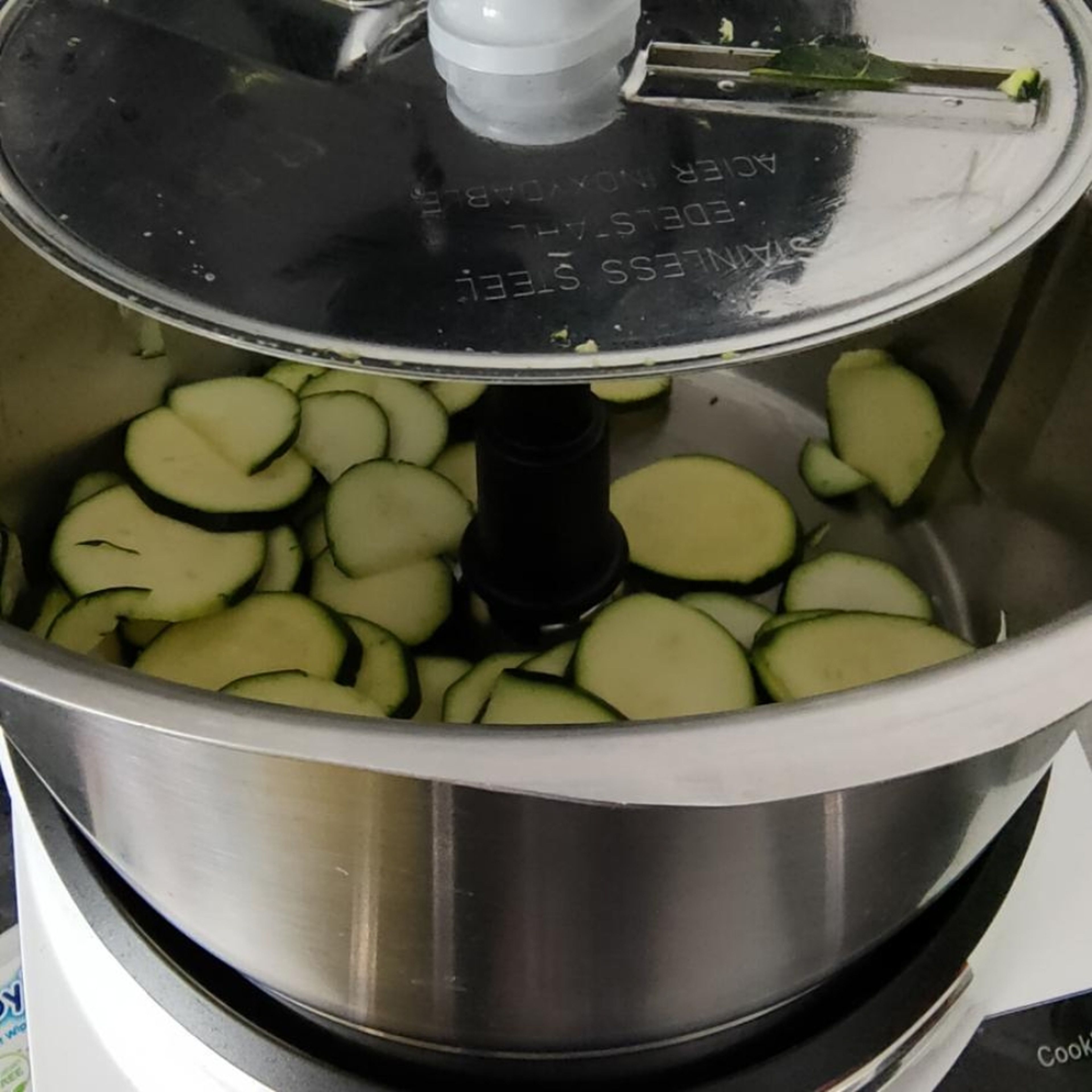 Den Zerkleinerungsaufsatz mit dicker Schneidscheibe einsetzen. Die Zucchini in die Einfüllöffnung geben, den Deckel schließen, den Messbecher einsetzen und in dicke Scheiben schneiden. (Zerkleinerungsaufsatz | Stufe 6|10 Sek)