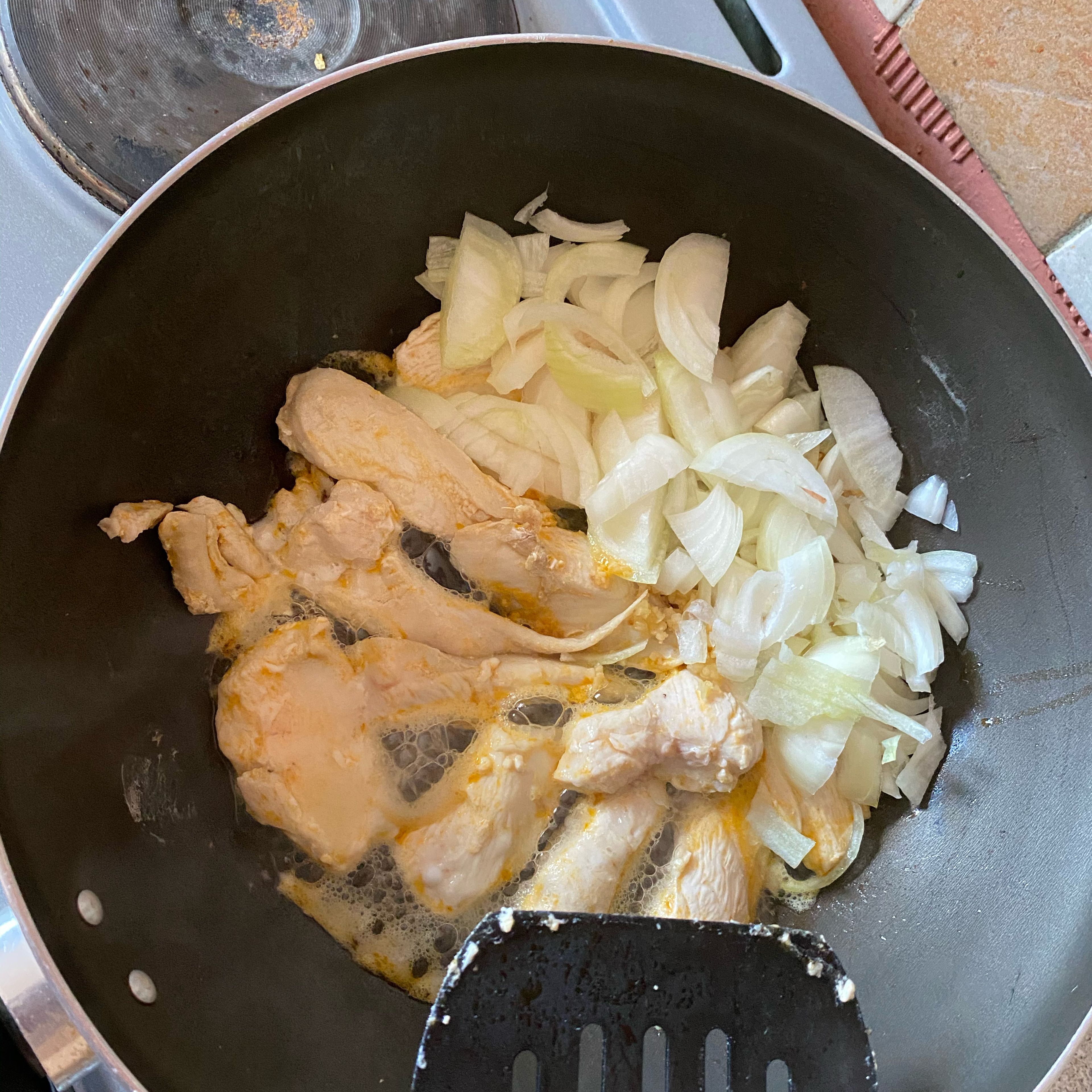 Slice the chicken into thin strips, lightly fry in olive oil. Then add the chopped onion to fry.