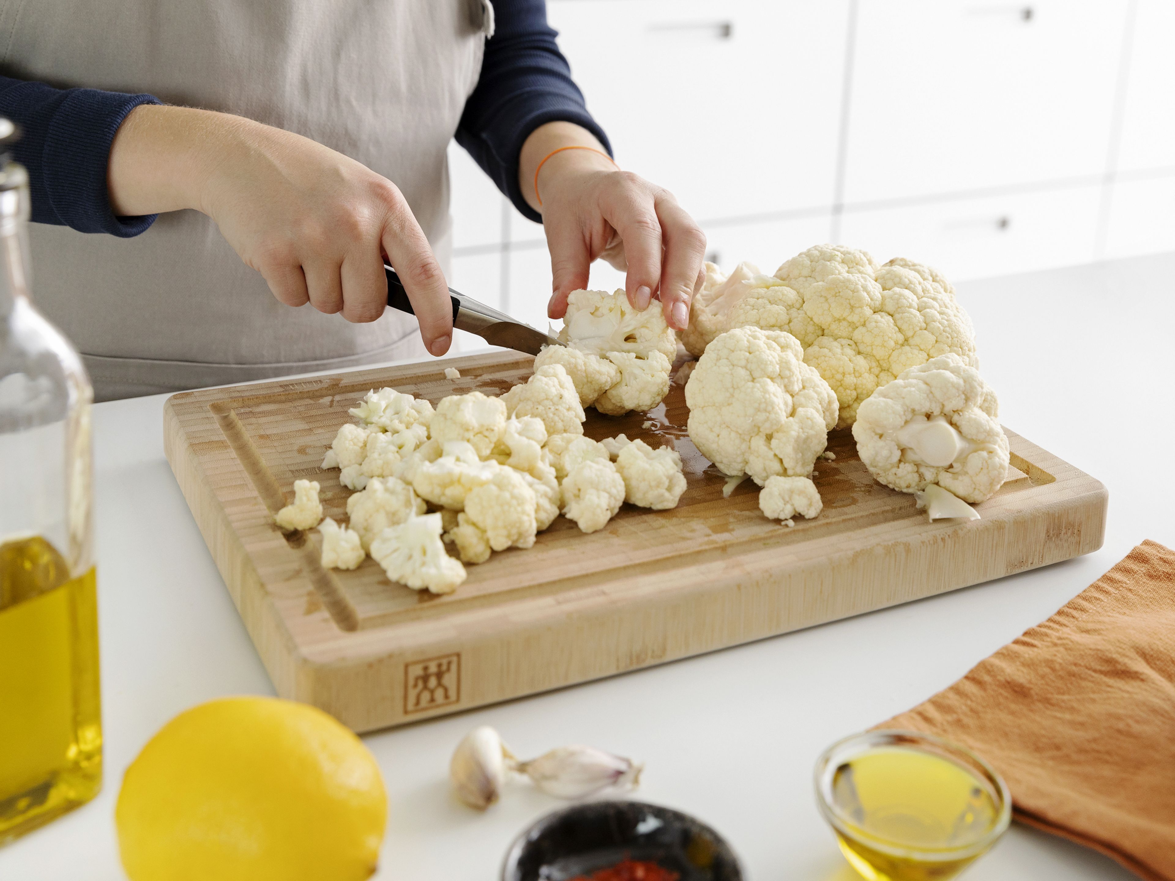 Den Ofen auf 180°C vorheizen. Den Blumenkohl in mundgerechte Stücke schneiden. Petersilie grob hacken. Die Zitronenschale und den Parmesan fein reiben.