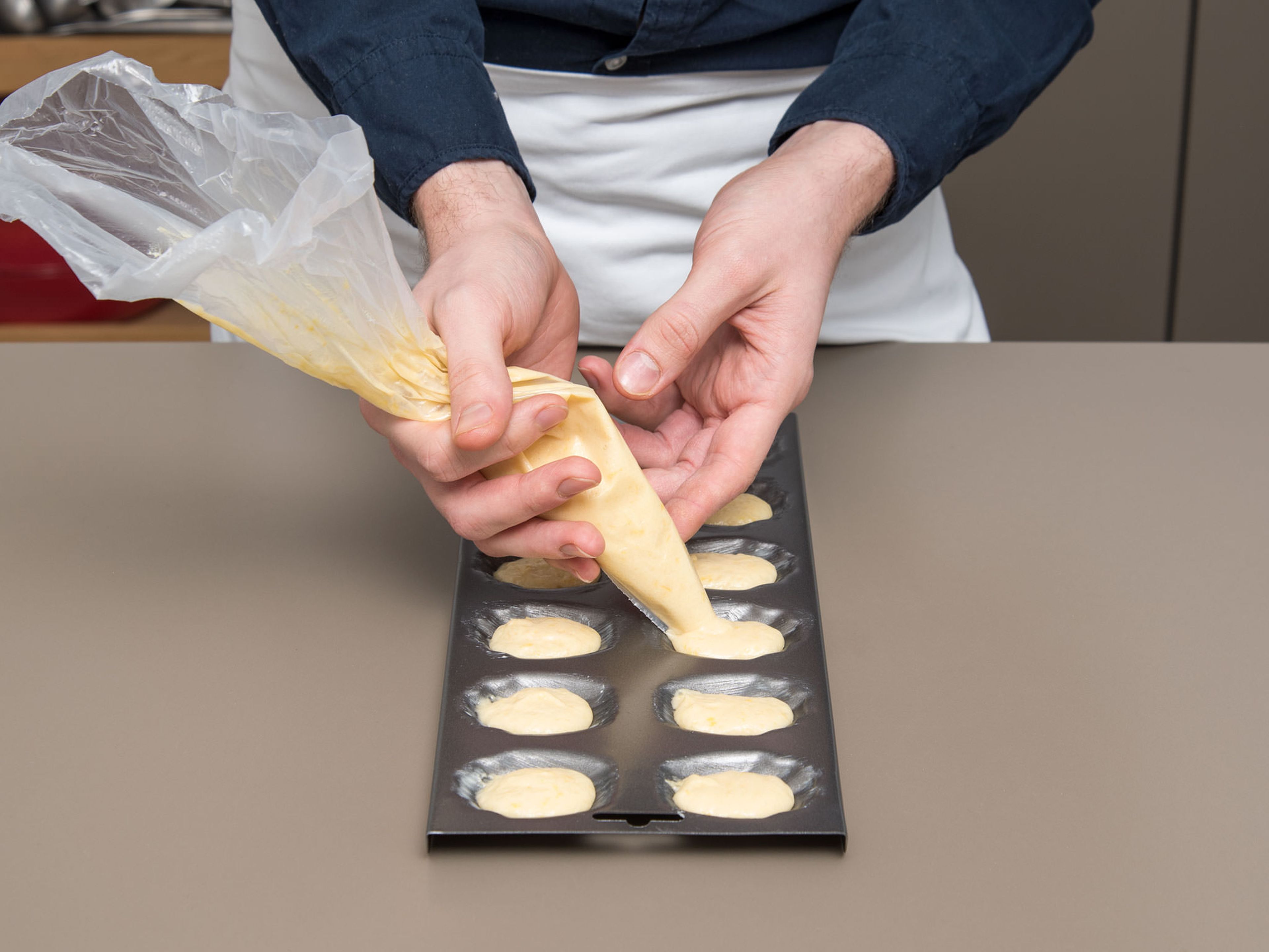 Pre-heat oven to 210°C/410°F. Grease baking pan with butter. Remove batter from the fridge and transfer into a piping bag. Cut off the tip and pipe batter into baking pan up to three quarters, so the madeleines have enough space to rise.