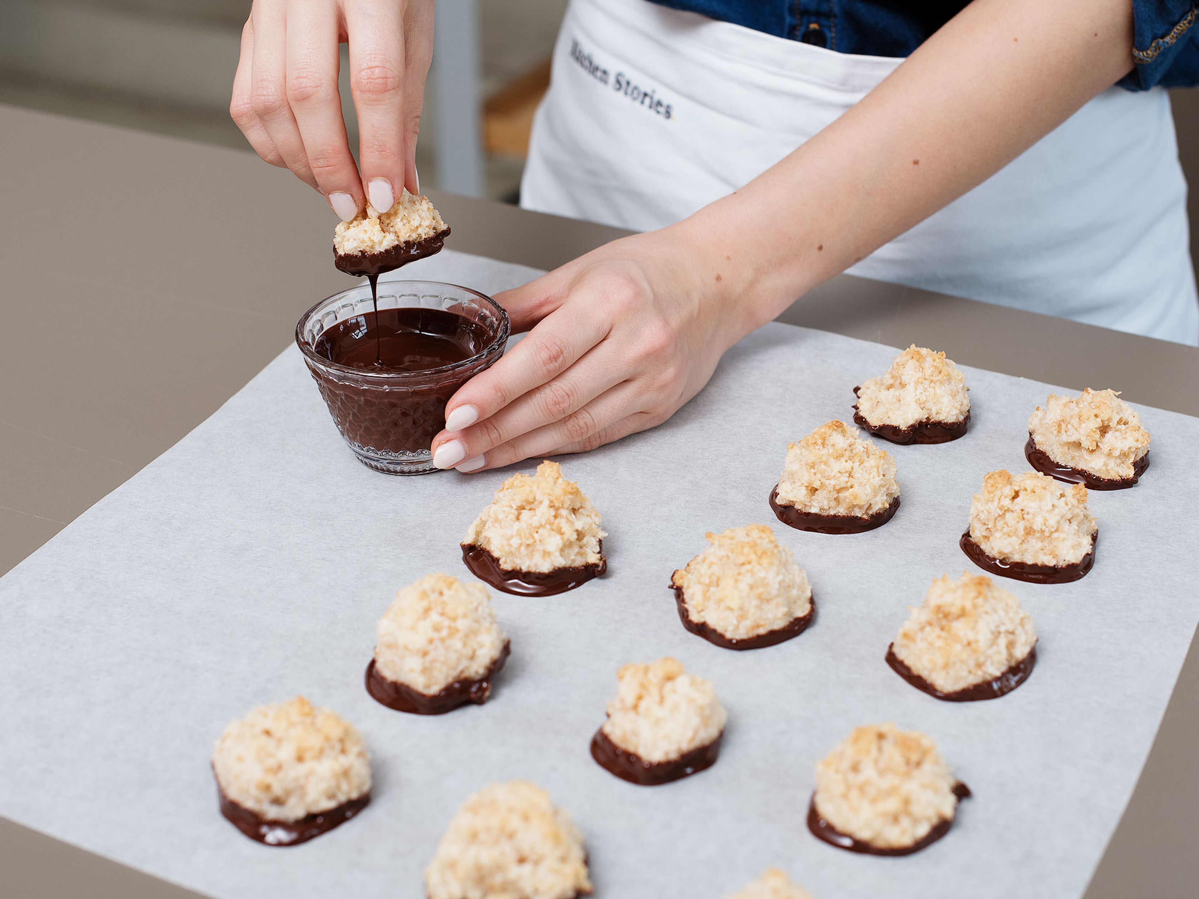 Break up chocolate and melt in a heatproof bowl set over a pot of simmering water. Carefully remove macaroons from baking paper and partially dip in chocolate. Place on parchment paper to dry for approx. 1 hr., then enjoy!