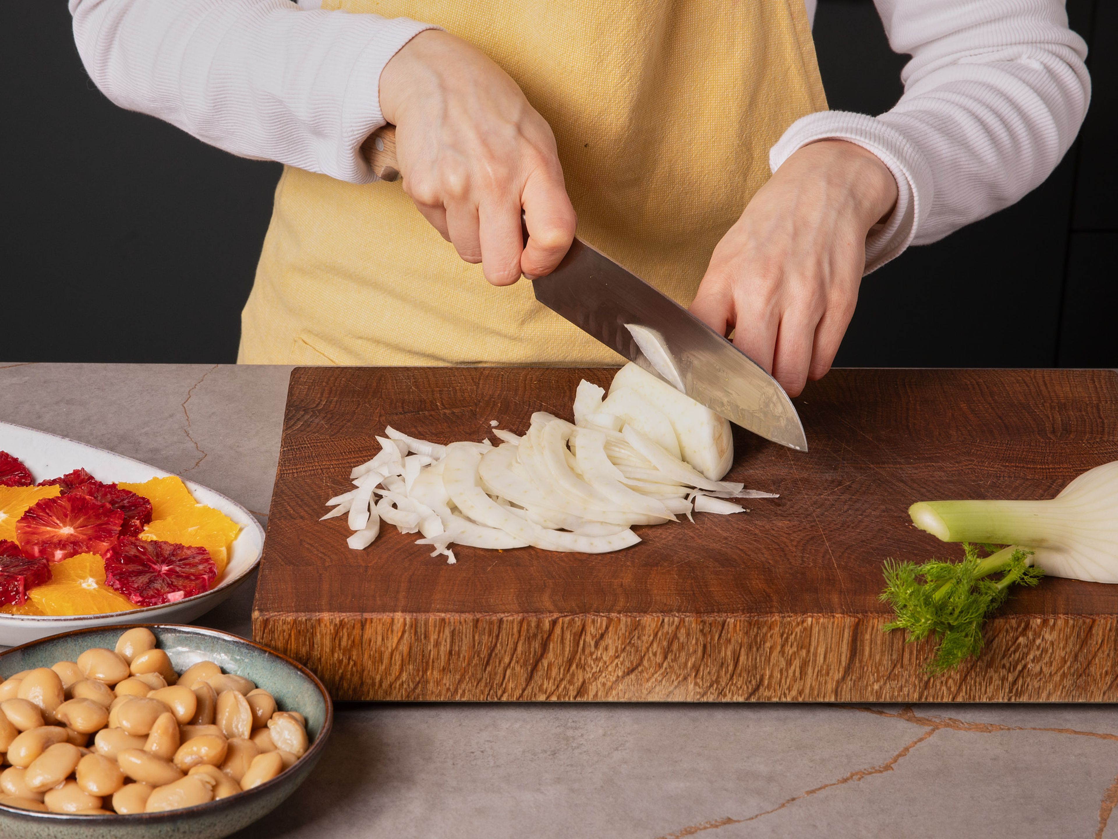 Nun alle weiteren Zutaten für den Salat vorbereiten: Die Bohnen abgießen, abspülen und abtropfen lassen. Den Fenchel in feine Ringe schneiden, die Orange filetieren und den Saft auffangen (ca. 1 EL pro Portion). Bohnen, Fenchel und Orangenfilets in eine große Schüssel geben und mit Essig und Salz vermengen.