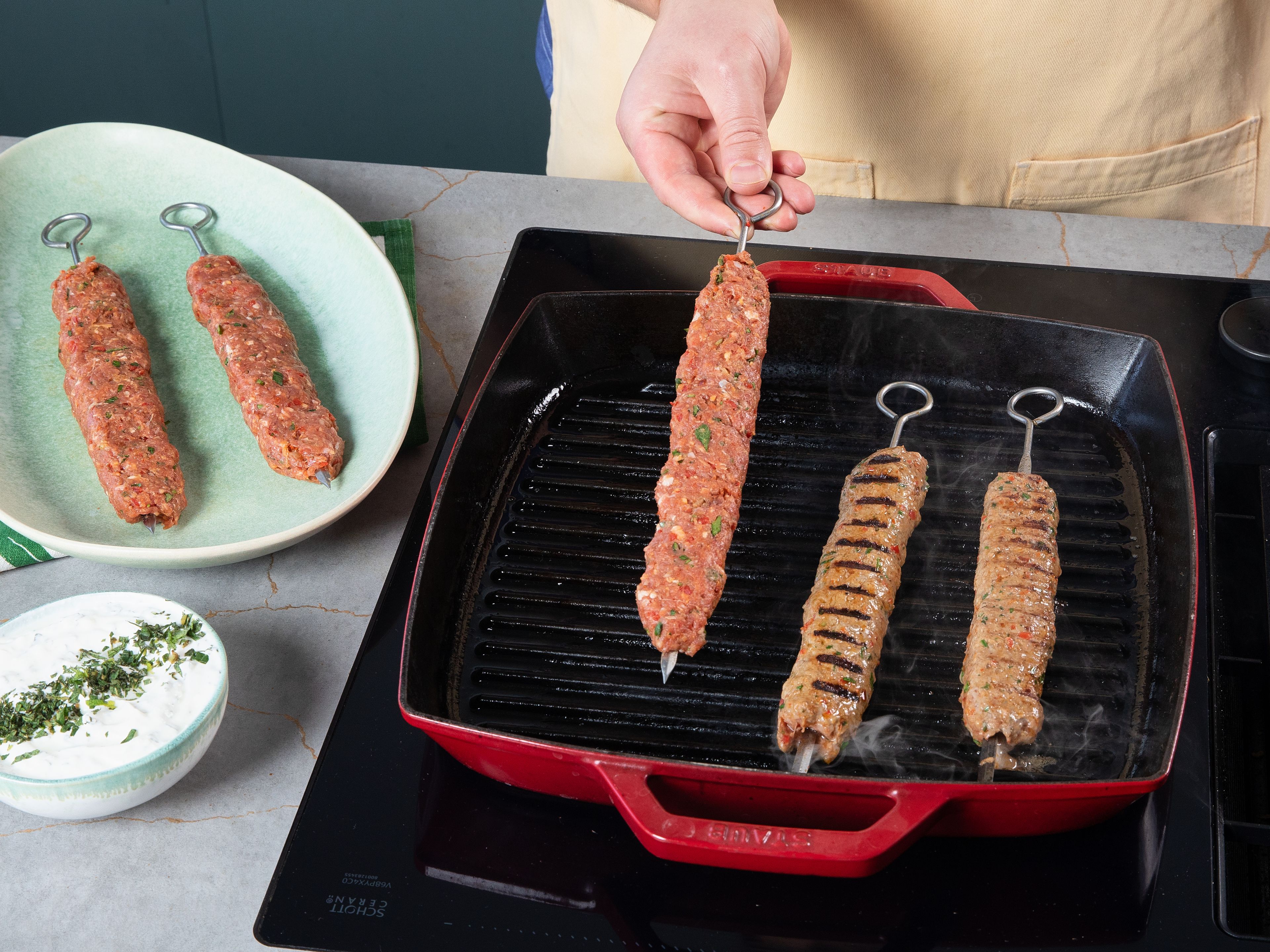 Den grill oder eine Grillpfanne vorheizen. Dann die Fleischspieße bei 230–250°C von beiden Seiten ca. 10–15 Min. je nach Dicke grillen. Tomaten halbieren und ebenfalls für ca. 5 Min. grillen. Die fertigen Spieße mit gegrillter Tomate und Zwiebelsalat servieren. Dazu passen nach Belieben Bulgur, Fladenbrot oder Joghurt-Minz-Soße (Cacık).