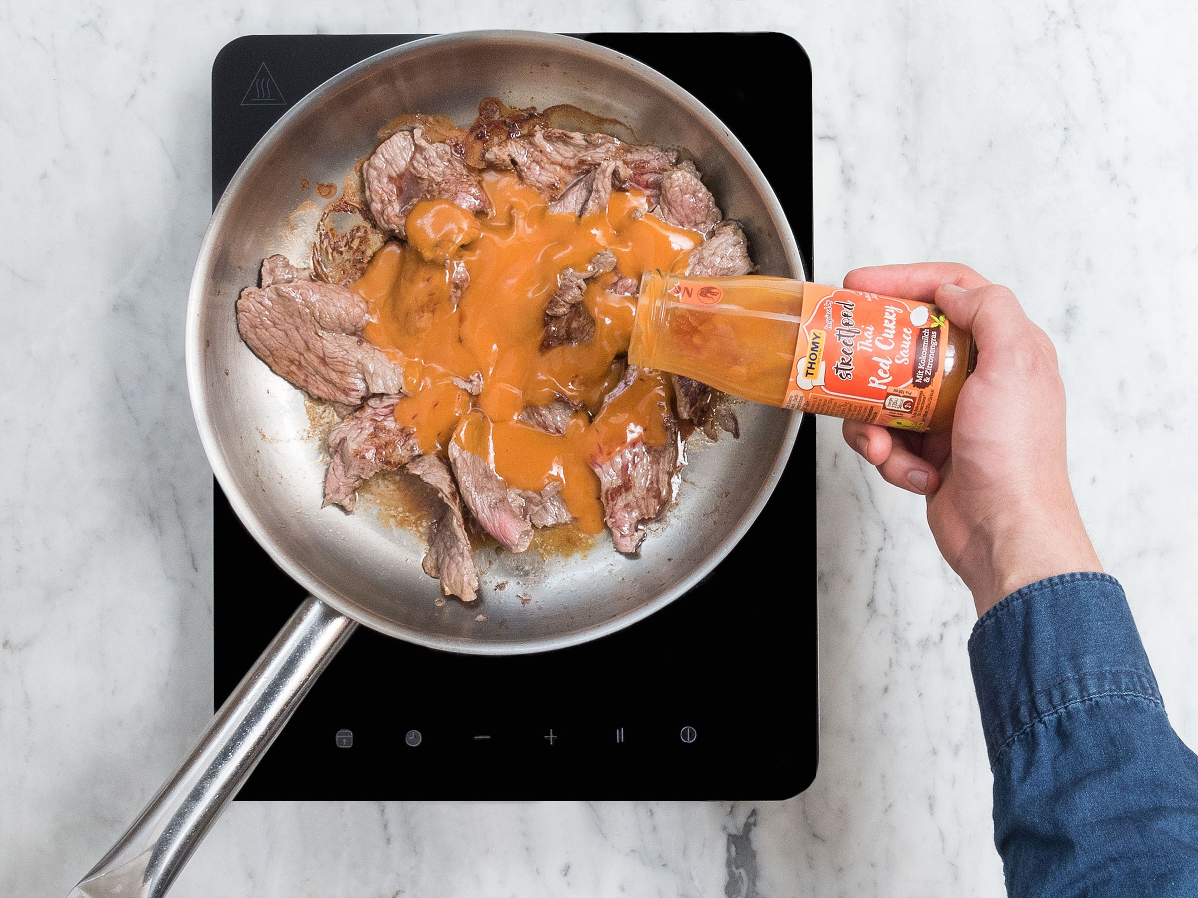 In a frying pan, heat vegetable oil over medium-high heat. Add beef strips and sear for approx. 2 – 3 min. Add Thai red curry sauce, reduce heat, and let simmer for approx. 3 – 5 min.