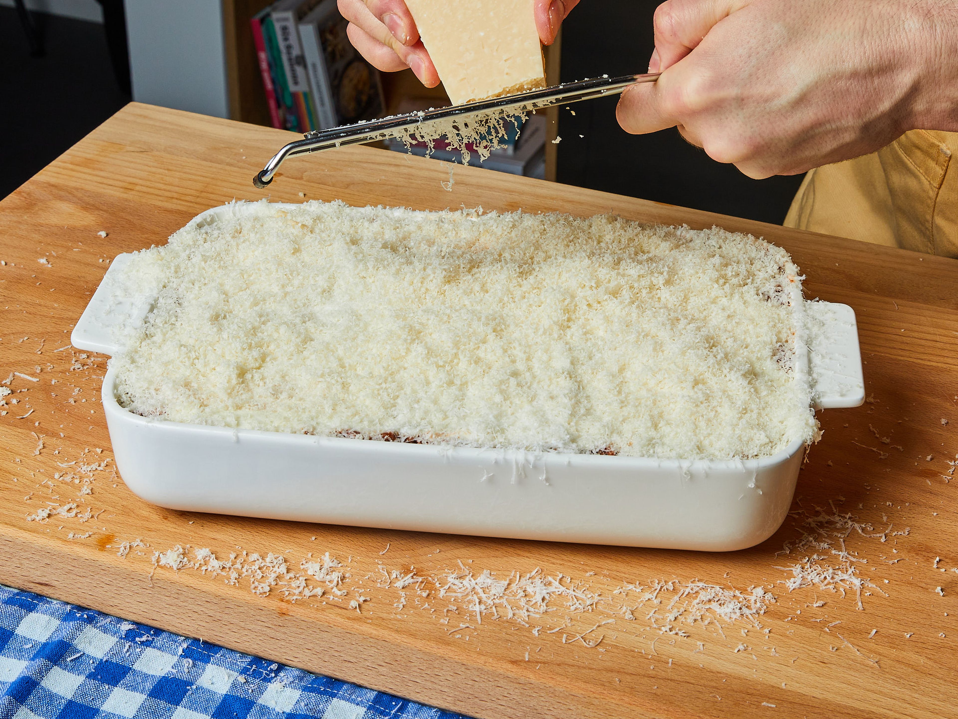 Den Parmesan über die letzte Schicht reiben. Die Lasagne auf der mittleren Schiene in den vorgeheizten Ofen schieben und ca. 30-40 Min. backen, bis die Oberfläche goldbraun ist. In der heißen Auflaufform servieren.