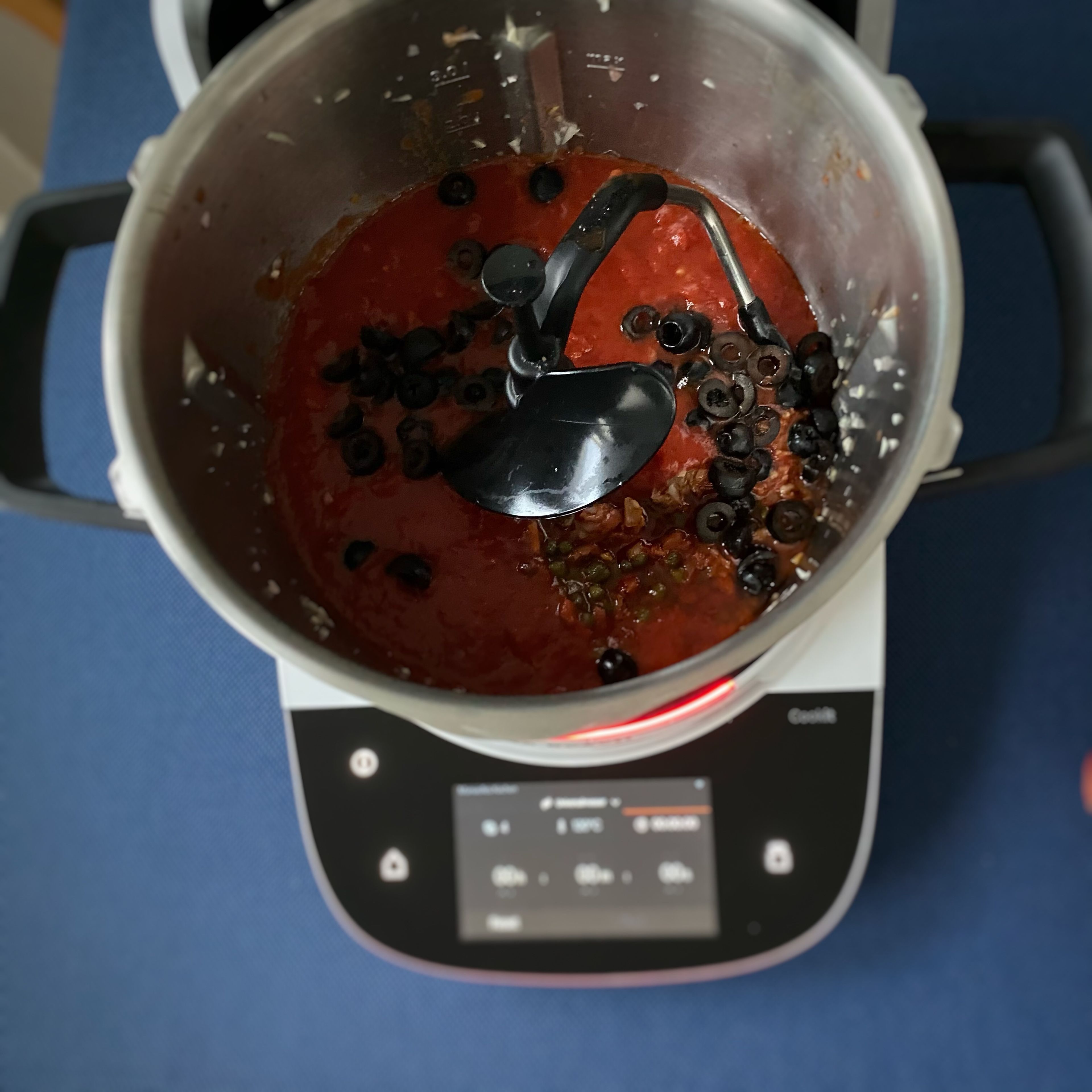 Die gehackten Tomaten, Kapern und Oliven dazugeben und kochen lassen (3D-Rührer | Stufe 4 | 98°C | 10 Minuten).