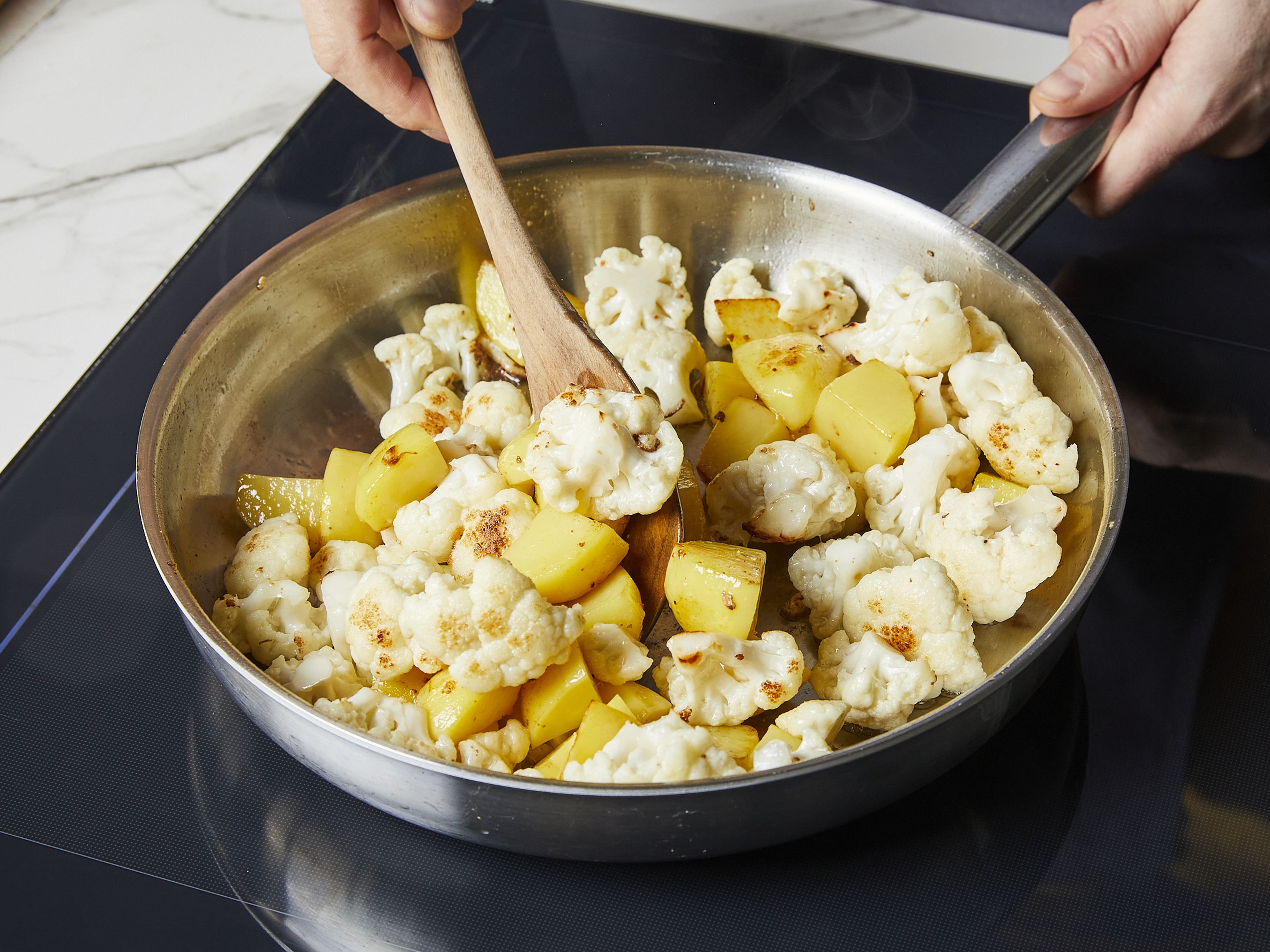 Heat half of the oil in a large pot or deep frying pan over medium heat. Add cauliflower florets and fry for approx. 2–3 min. Then add the potatoes. Fry over medium heat for approx. 7–8 min., until potatoes and cauliflower start browning. Remove from pan and set aside.