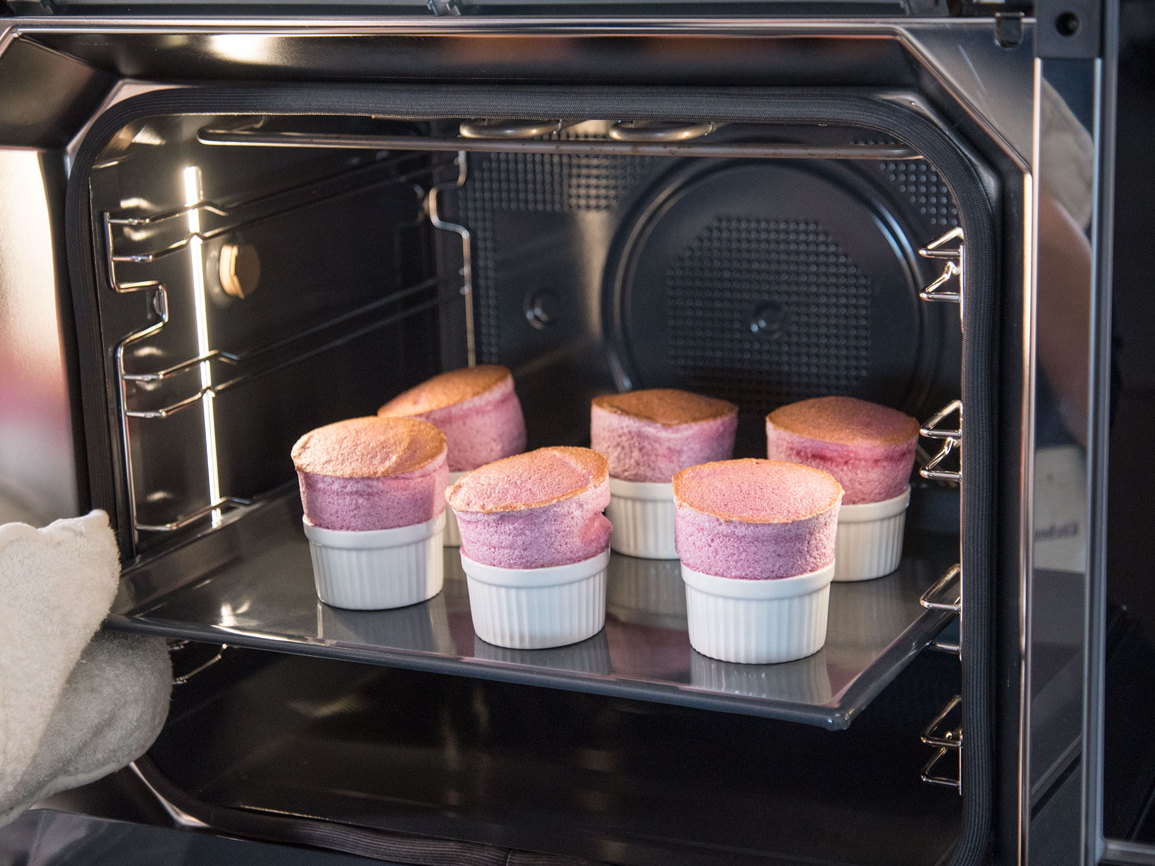Divide the batter evenly between the soufflé forms and smooth out the tops. Place the filled forms on the baking sheet and transfer to preheated oven. Bake for approx. 14 min.