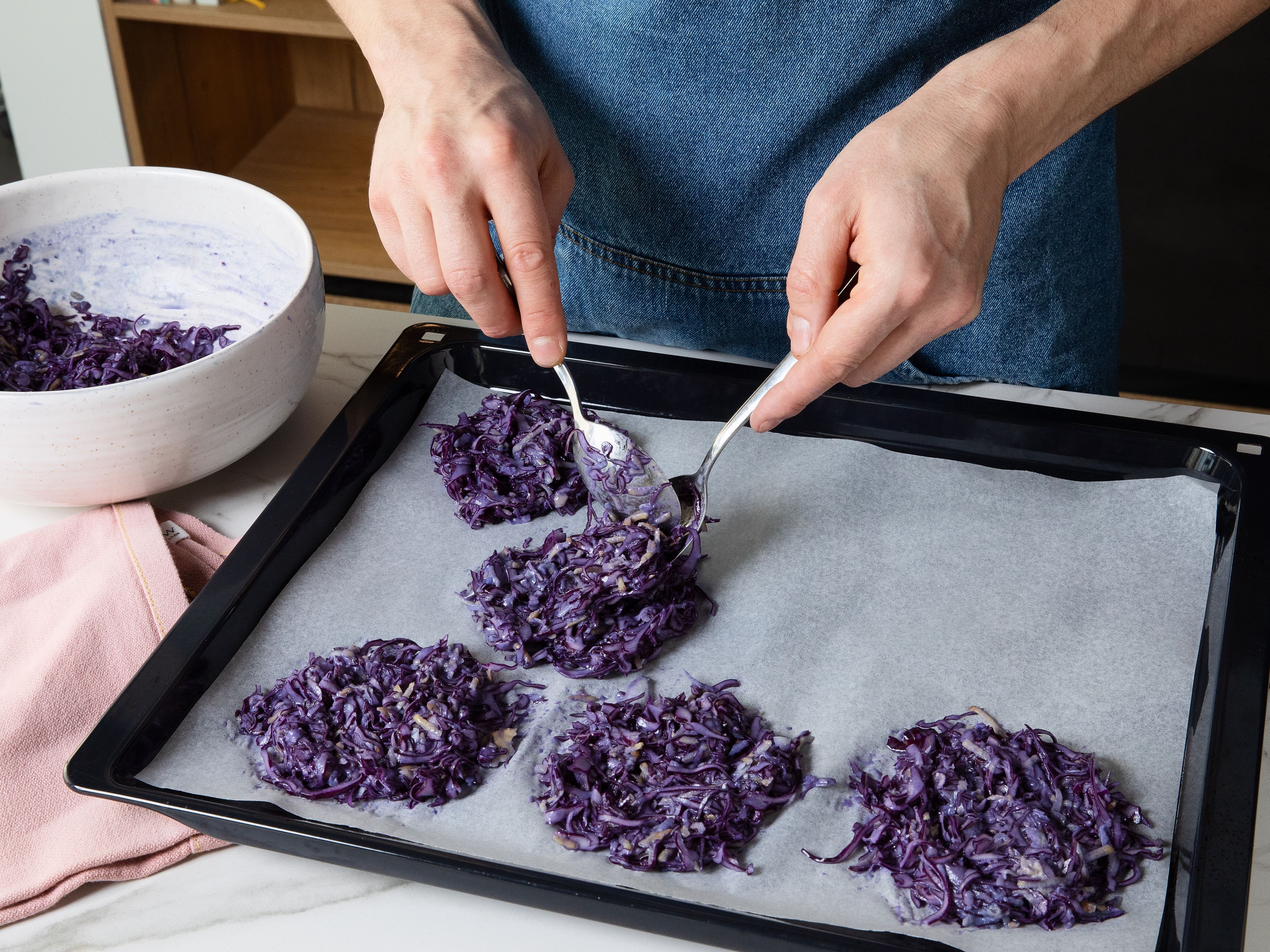 Den geschnittenen Rotkohl und die Kartoffeln mit Eiern, Mehl, Salz, Pfeffer und Muskatnuss in einer Schüssel vermengen. Kleine Portionen der Mischung mit einem Löffel auf ein mit Backpapier ausgelegtes Backblech geben. Mit Öl beträufeln und ca. 20 Min. goldbraun backen, dabei einmal wenden. Während des Backens mit dem Rezept fortfahren.