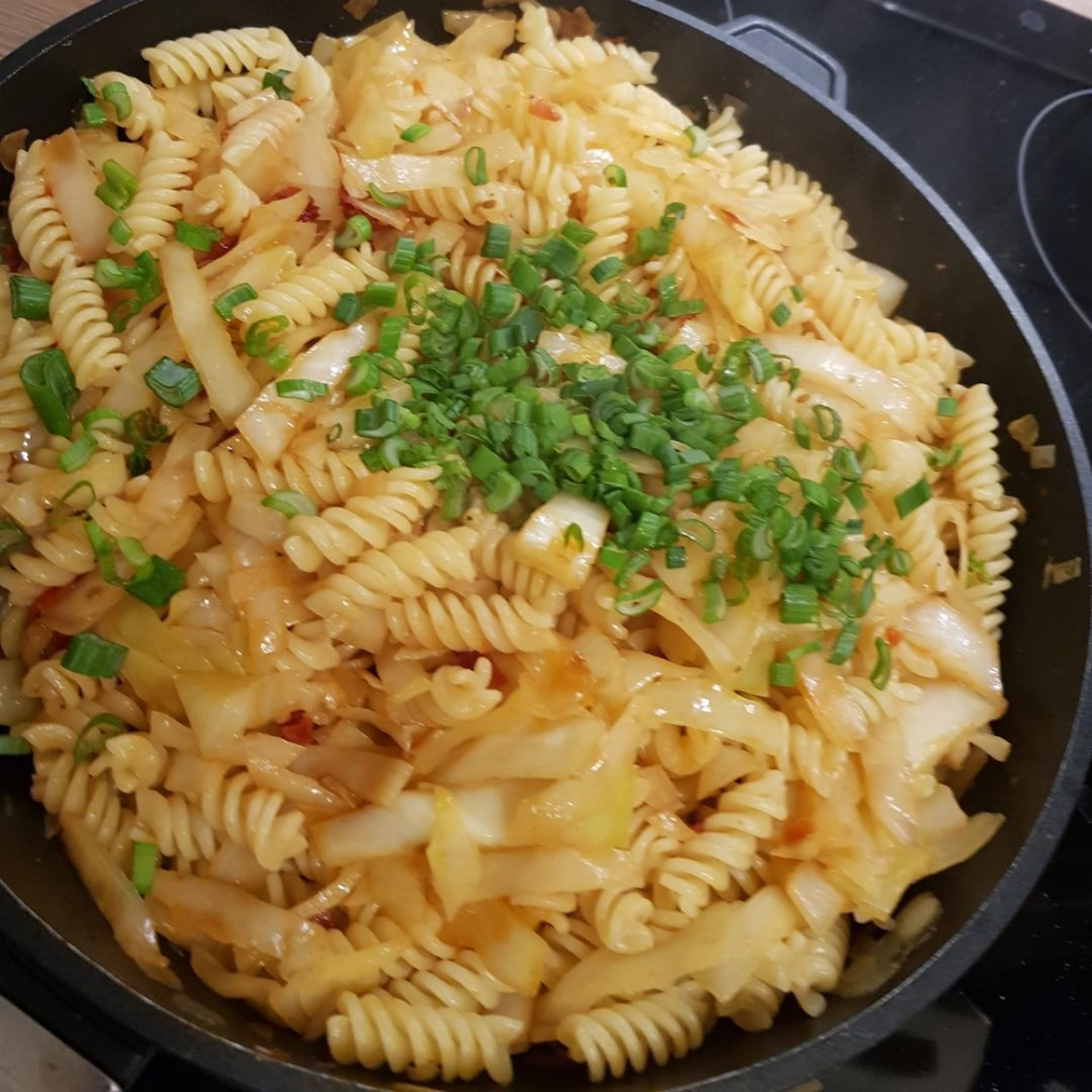 Nun die Nudeln zum Kohl geben, alles vermengen und anrichten! Mit Kräutern und gerösteten Nüssen garnieren.