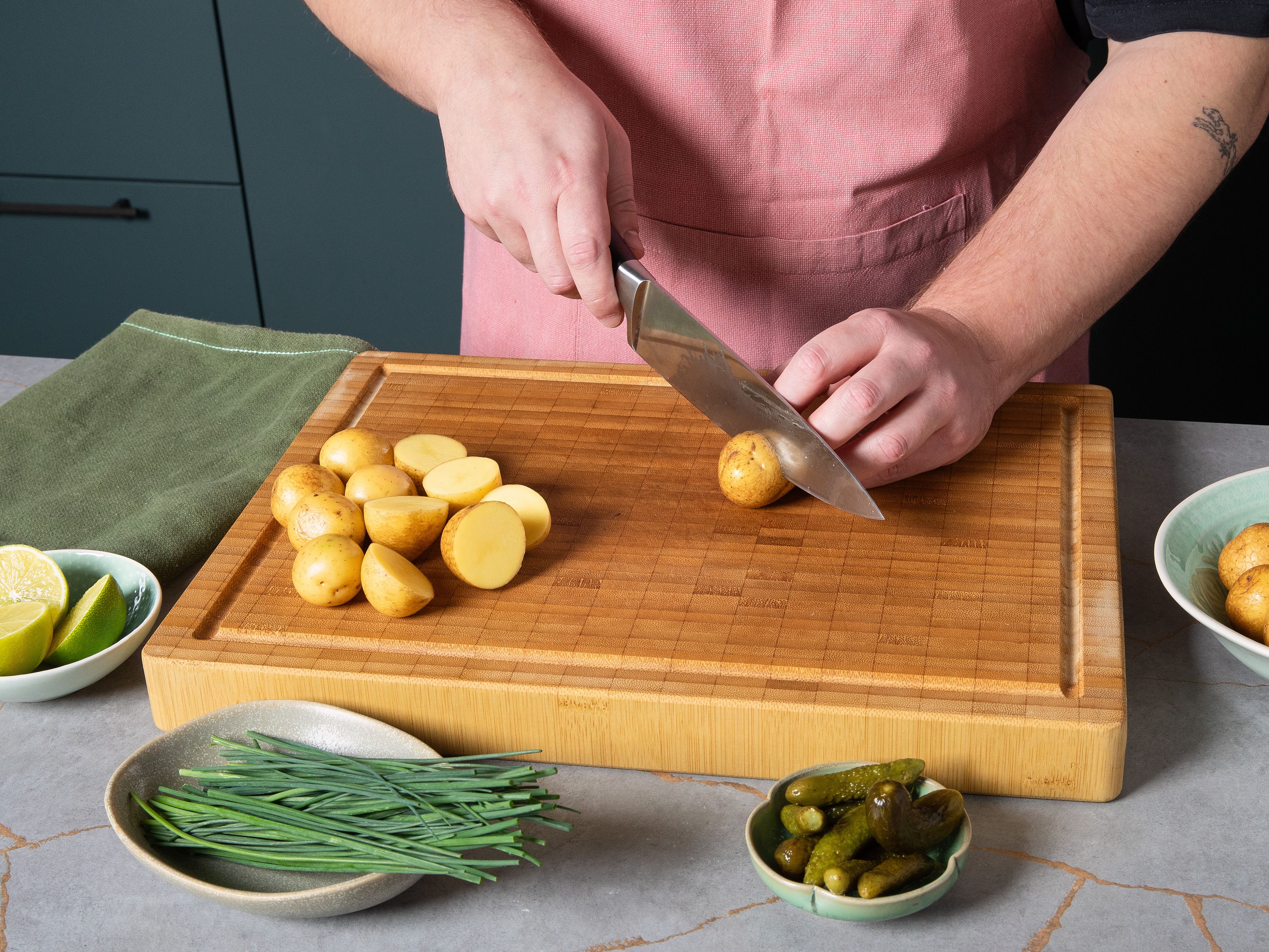 Start this potato salad by cutting large potatoes in half. Then place them in a pot and cover with cold water. Add plenty of salt and bring to a boil over high heat. Once it boils, reduce the heat slightly, cover and simmer for approx. 15 min. until the potatoes are soft. Then drain and leave to cool.