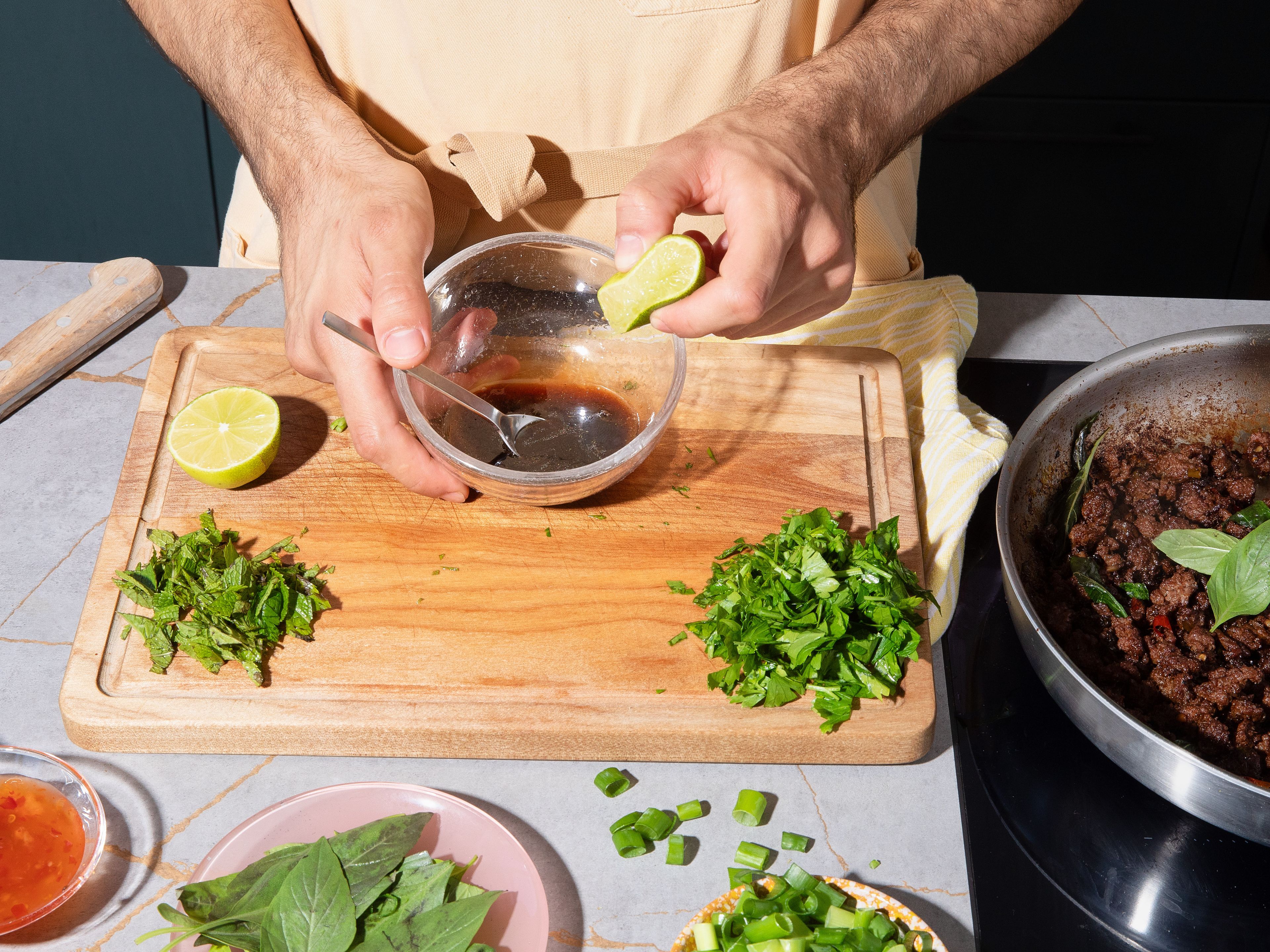 While the beef is frying, chop mint and cilantro. Set the herbs aside for the filling. For the dipping sauce, mix the remaining soy sauce, sesame oil, sesame seeds, remaining sweet chili sauce, and lime juice in a small bowl.