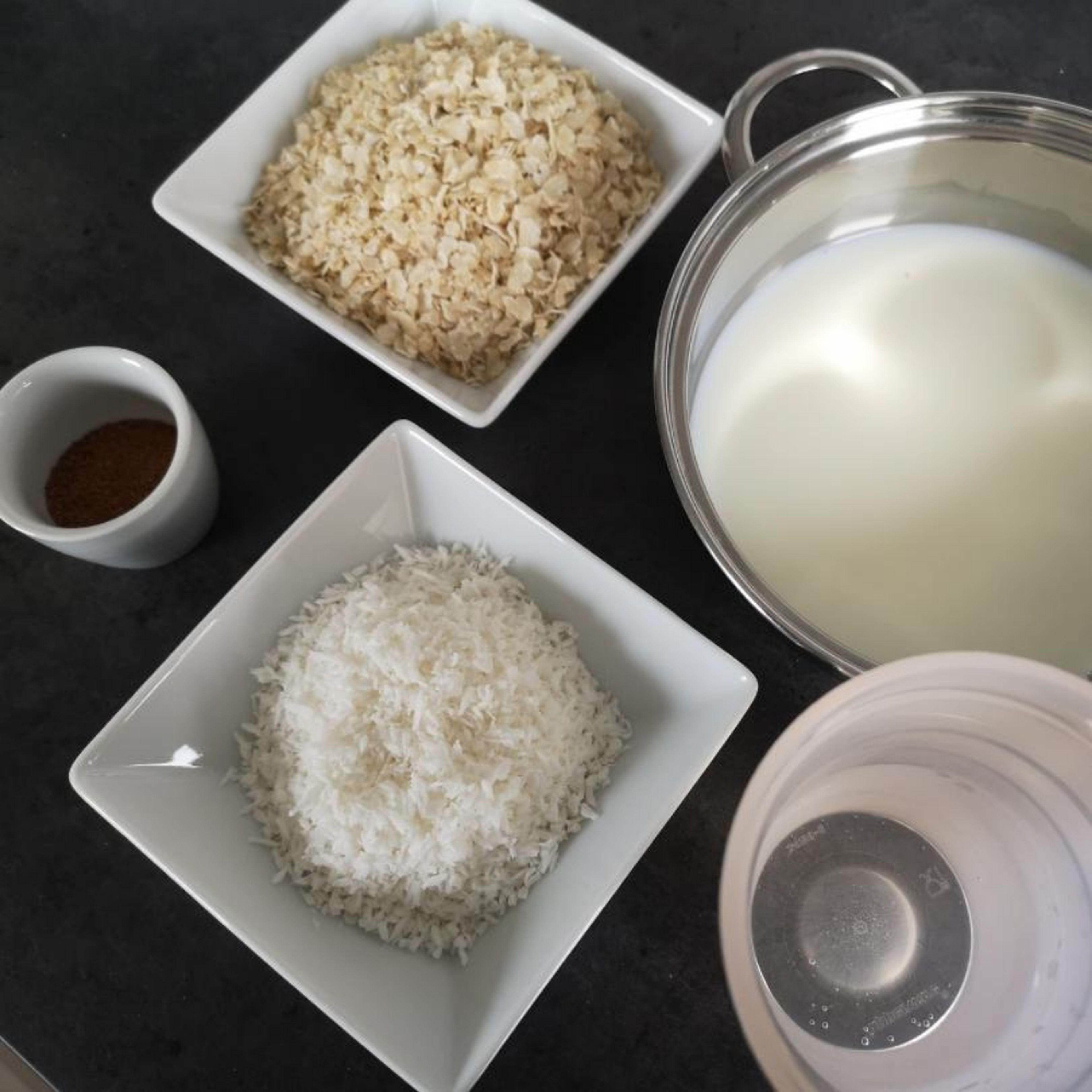Reisflocken, Kokosraspel und Kokosblütenzucker mit der Milch und dem Wasser unter ständigem Rühren köcheln lassen.
