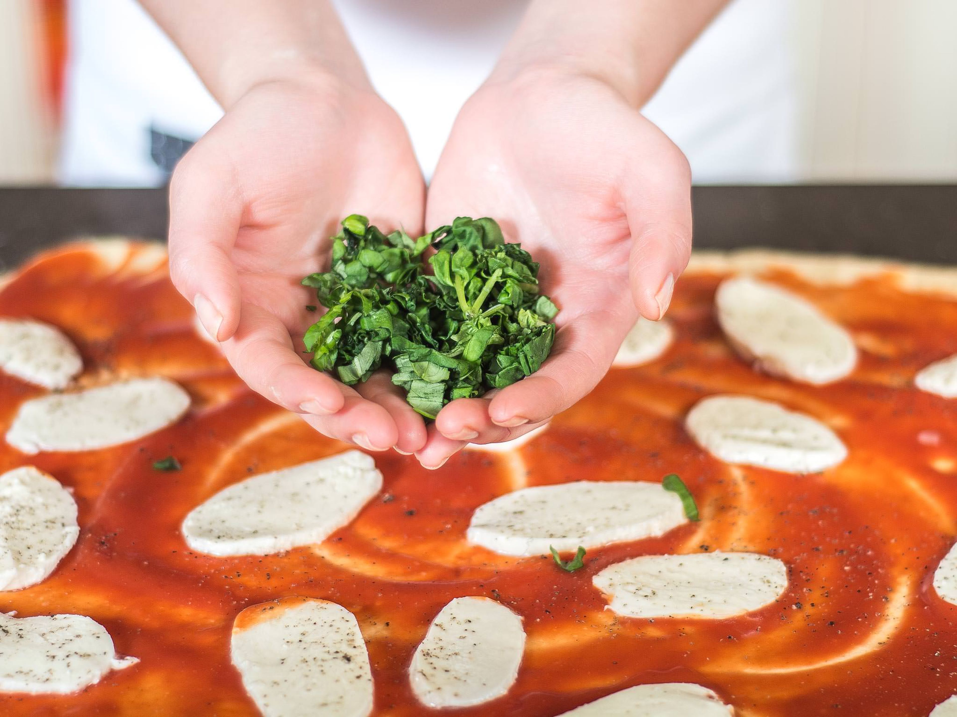Mozzarellascheiben und Basilikumstreifen gleichmäßig auf den passierten Tomaten verteilen. Alles kräftig salzen und pfeffern.