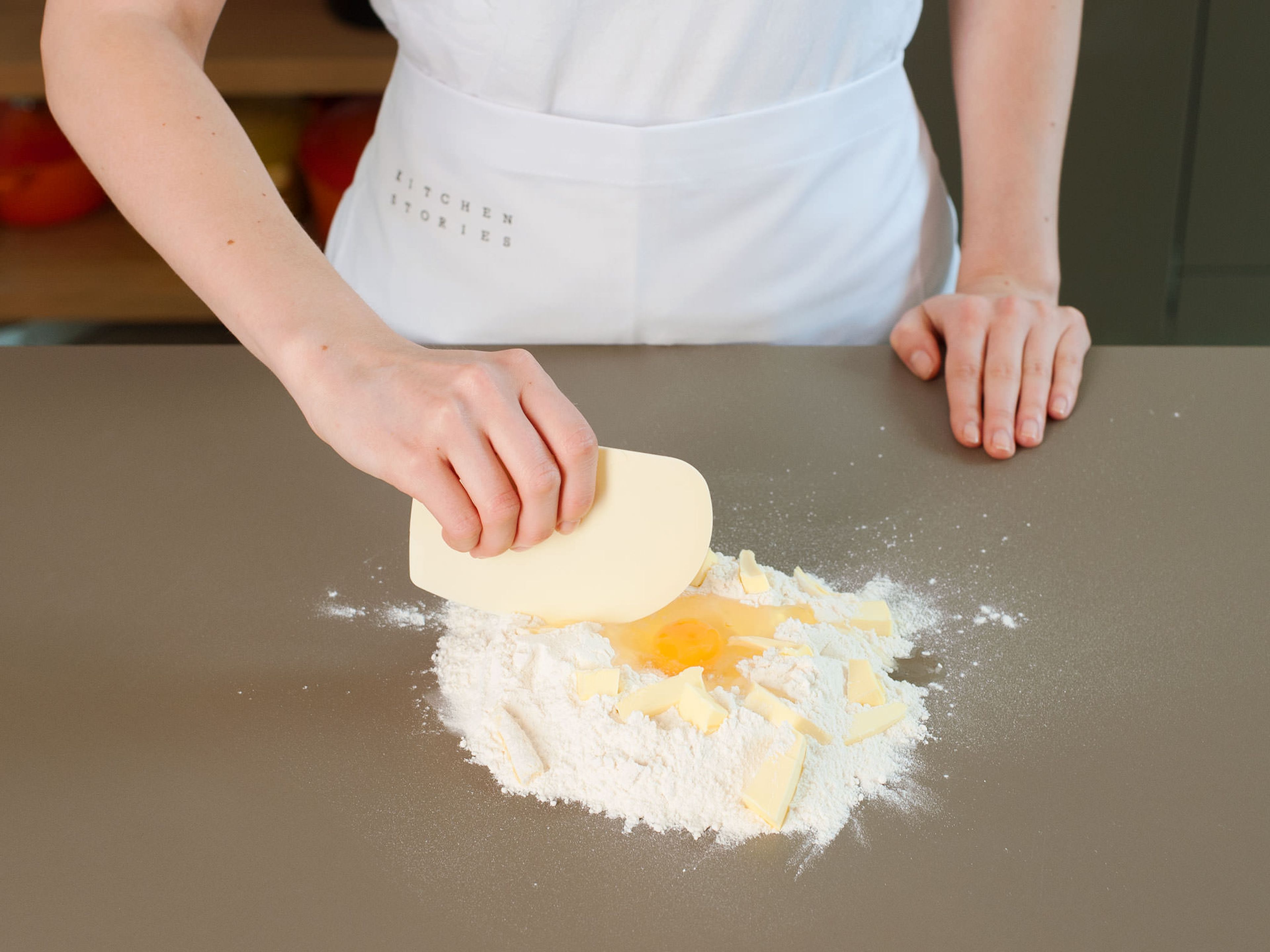 Mehl und Salz vermengen, auf eine Arbeitsfläche geben und zu einem Hügel mit einer Einbuchtung in der Mitte formen. Ein Ei in die Einbuchtung geben. Butter in grobe Stücke schneiden, auf dem Mehl verteilen und anschließend mit dem Teigschaber einarbeiten. Mit den Händen alle Zutaten gut miteinander vermengen, bis sich ein gleichmäßiger Teig bildet. In eine flache Scheibe pressen, ein Frischhaltefolie einschlagen und für ca. 30 Min. in den Kühlschrank geben.