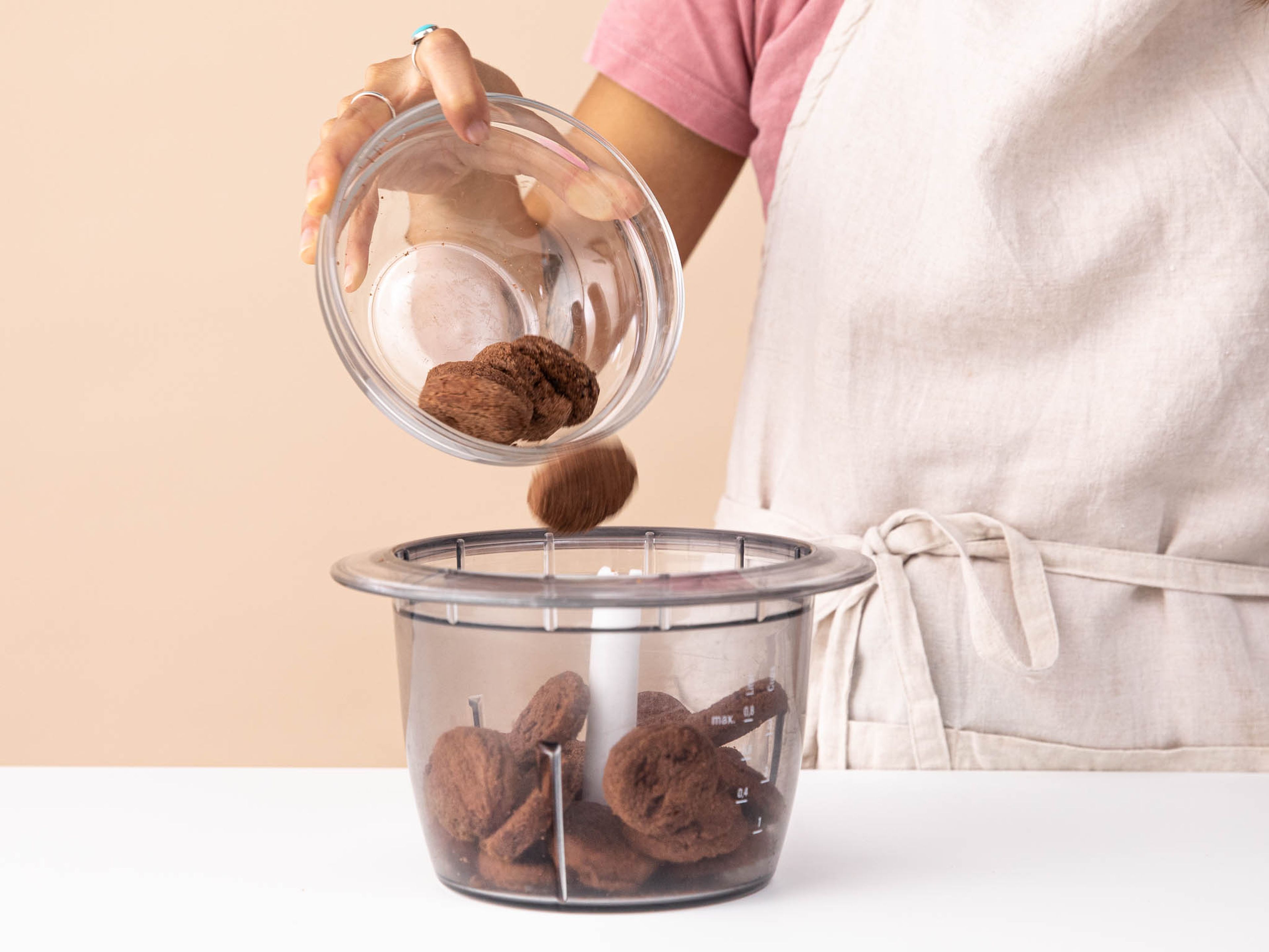 Schokoladenkekse in einem Zerkleinerer mit der Pulsfunktion zu einem groben Pulver verarbeiten. Die zerkleinerten Kekse in eine Schüssel geben.
