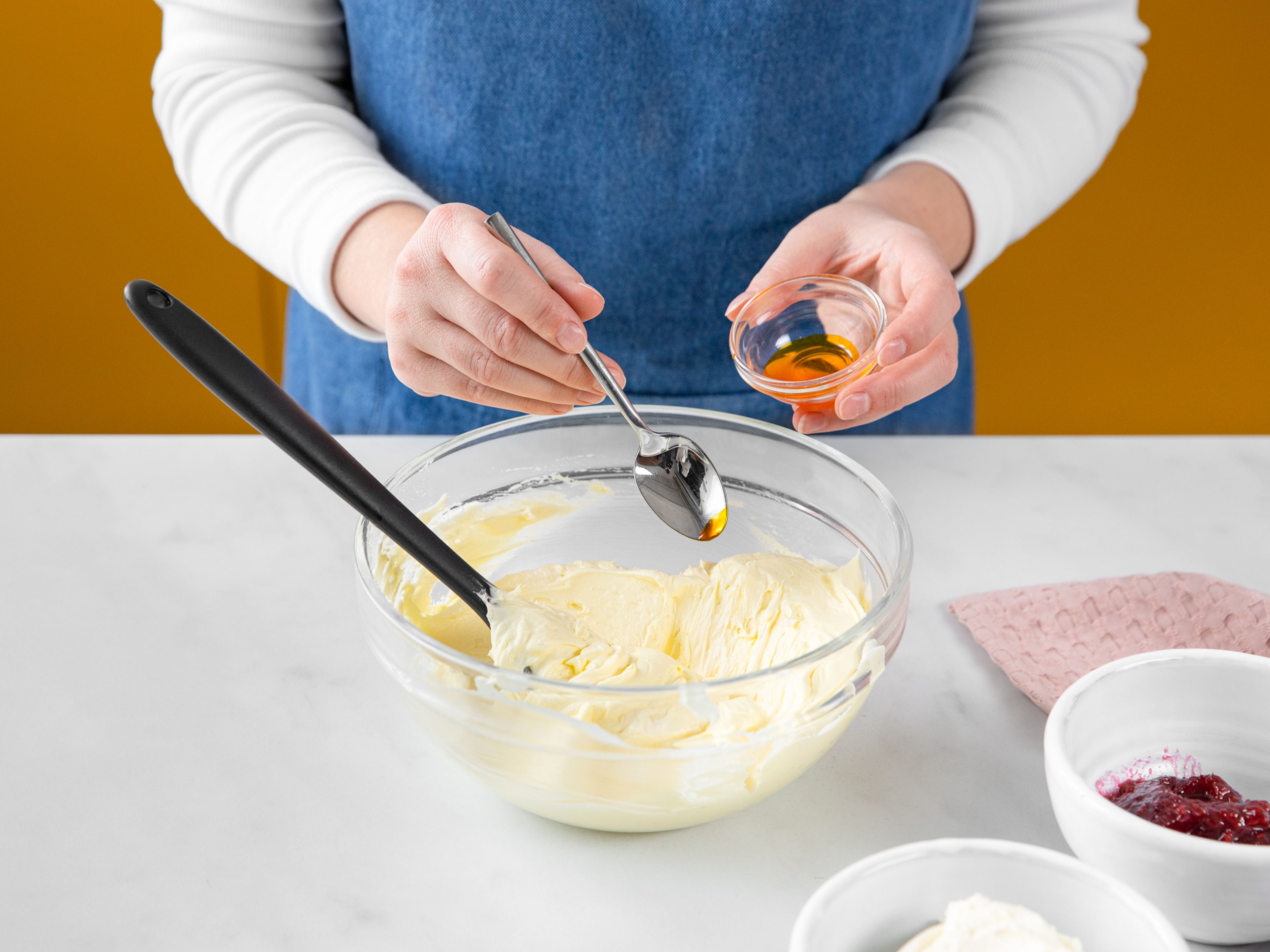 Für die Buttercreme die Butter mit dem Puderzucker, Vanilleextrakt und Salz in der Küchenmaschine schaumig aufschlagen. Zwei Drittel der Buttercreme in eine andere Schüssel füllen und gelb einfärben. Das andere Drittel in der Küchenmaschine mit Frischkäse verrühren und rosa einfärben. Beide in Spritzbeutel füllen.
