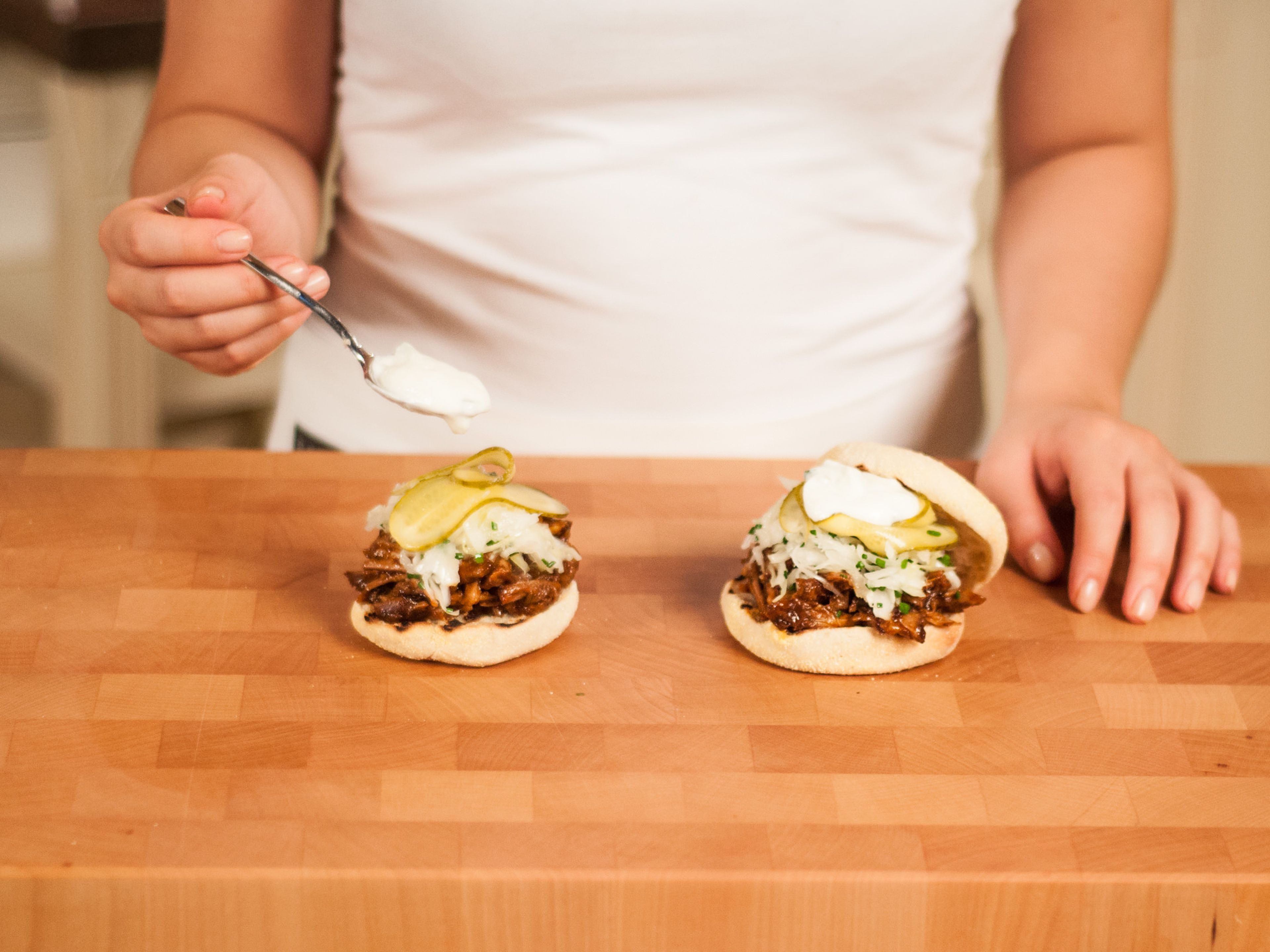 Preheat a grill pan over medium heat. Grill buns for approx. 1 - 2 min. on each side. Place shredded pork onto the bun. Serve topped with cabbage, pickles, and sour cream.