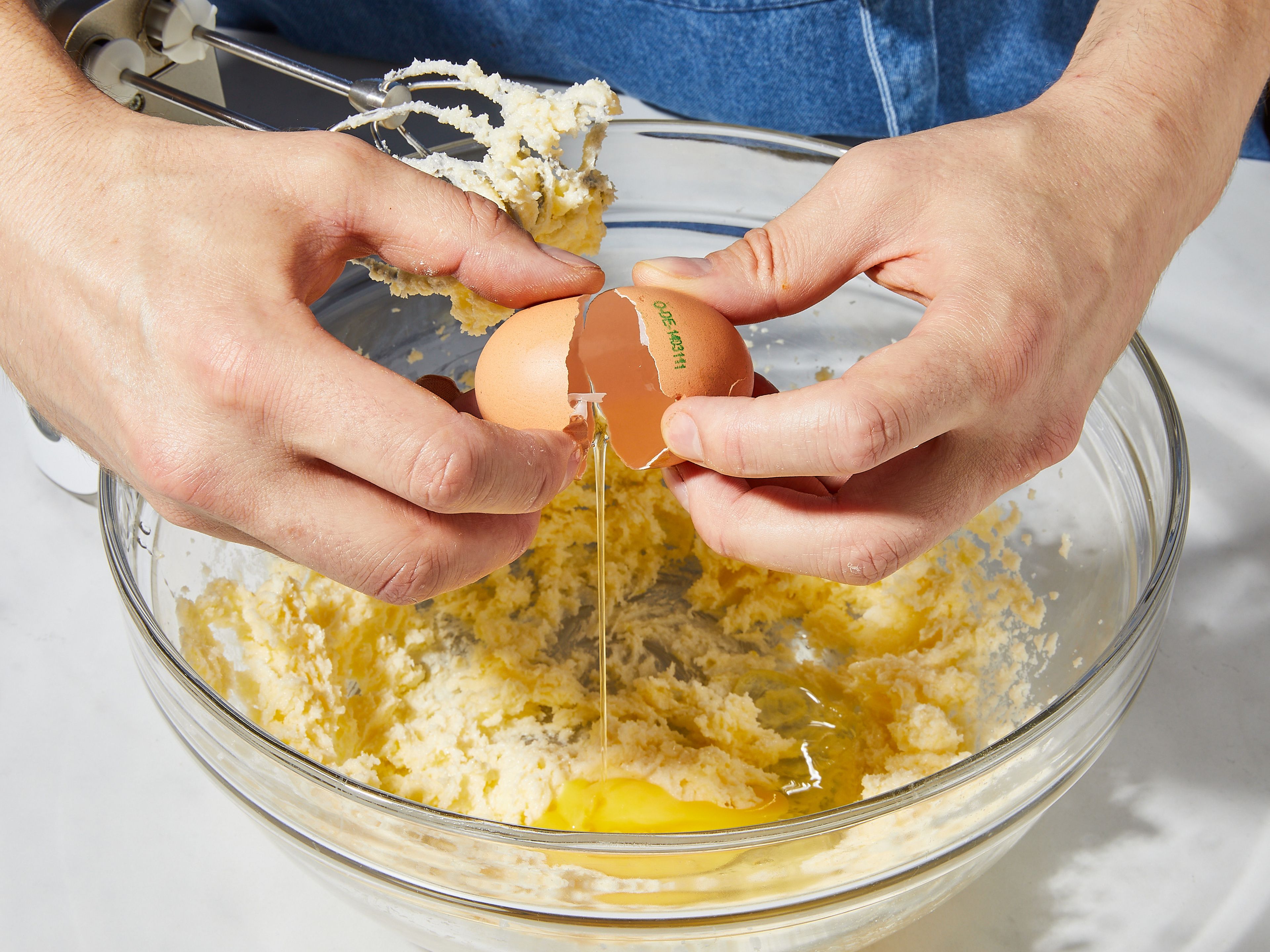 Den Backofen auf 180°C Ober-/Unterhitze vorheizen. Springform einfetten und mit Mehl bestäuben. 1 TL Zitronenschale fein abreiben. In einer großen Schüssel Butter, den größten Teil des Zuckers, eine Prise Salz und die Zitronenschale vermischen und mit einem Handrührgerät oder dem Standmixer auf höchster Stufe mindestens ca. 3 Min. lang schlagen. Nach und nach die Eier hinzugeben und weiterschlagen. Dann Mehl und Backpulver hinzugeben und alles zu einem glatten und klumpenfreien Kuchenteig verrühren.