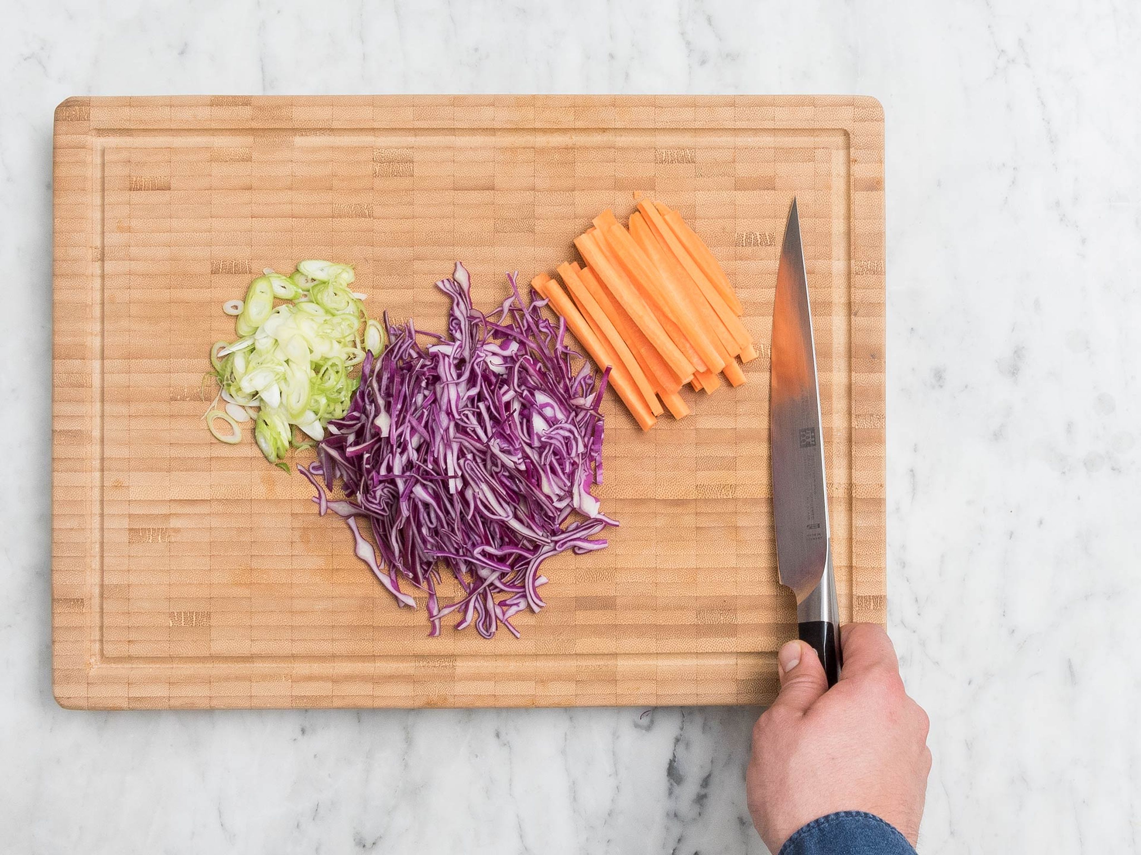 Add rice to pot, cover with water, and cook for approx. 12 – 15 min. Meanwhile, cut red cabbage into fine strips. Peel, halve, and julienne carrots. Slice green onions into thin rings.