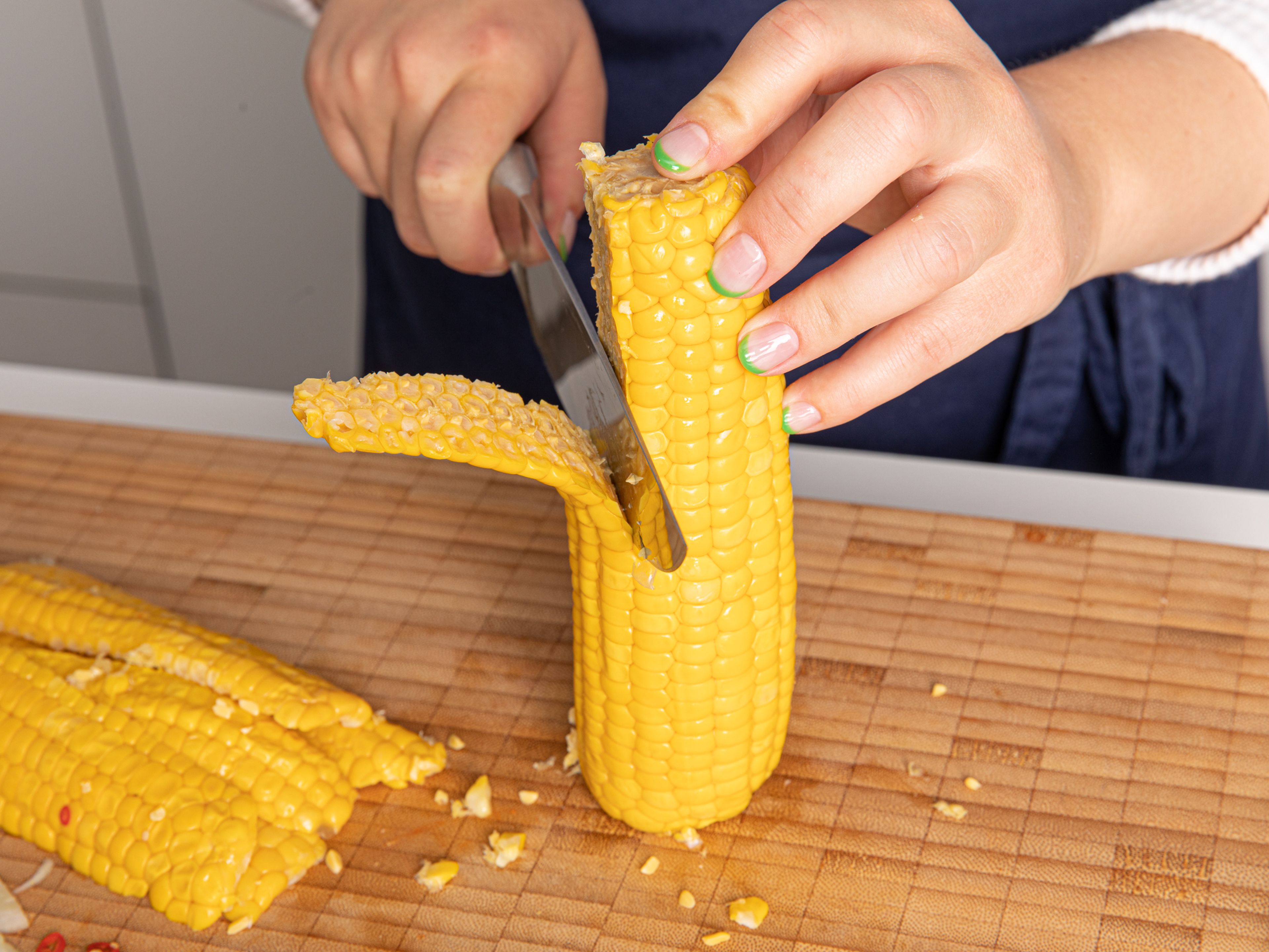 Peel onion, halve, and slice. Peel and slice garlic. Slice scallion. Place the corn cobs upright onto a cutting board and carefully use a knife to slice the kernels straight down off the cob. Thinly slice chili.