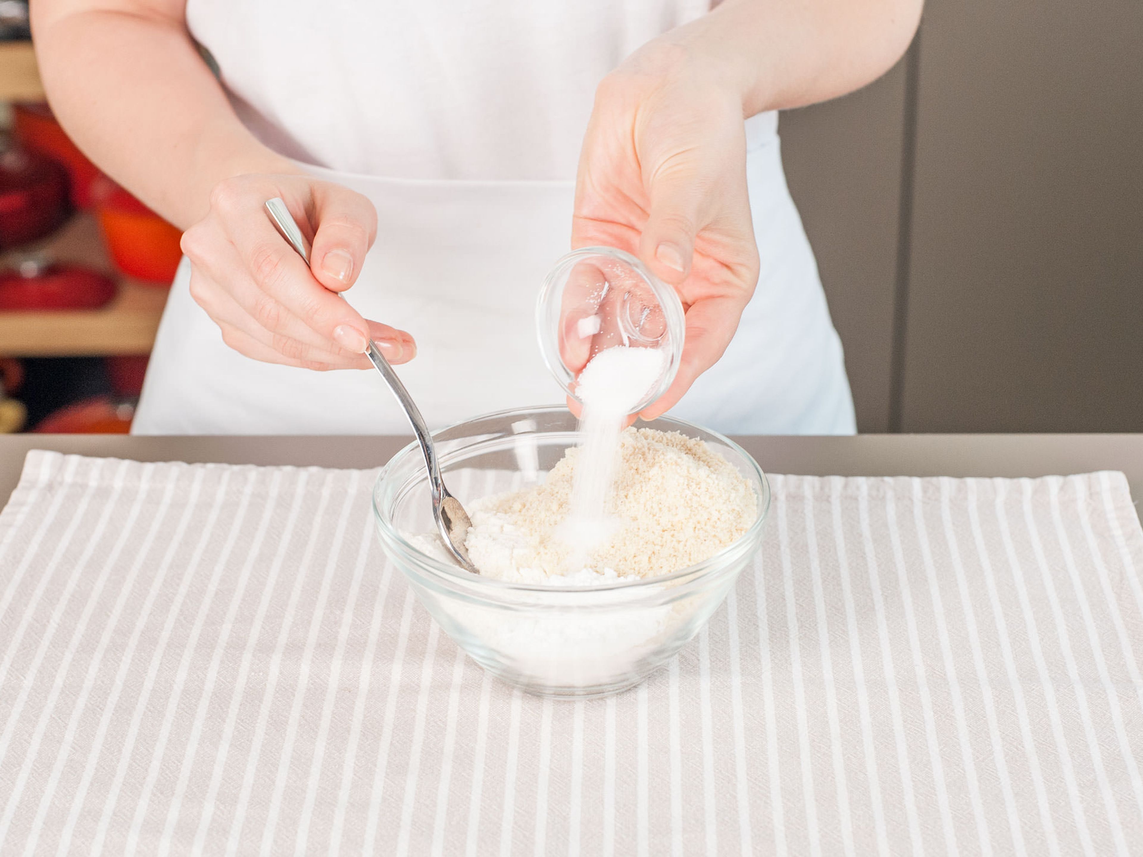 Einen Teil des Mehls, gemahlene Mandeln, Backpulver und einen Teil des Salzes in einer Rührschüssel vermengen.