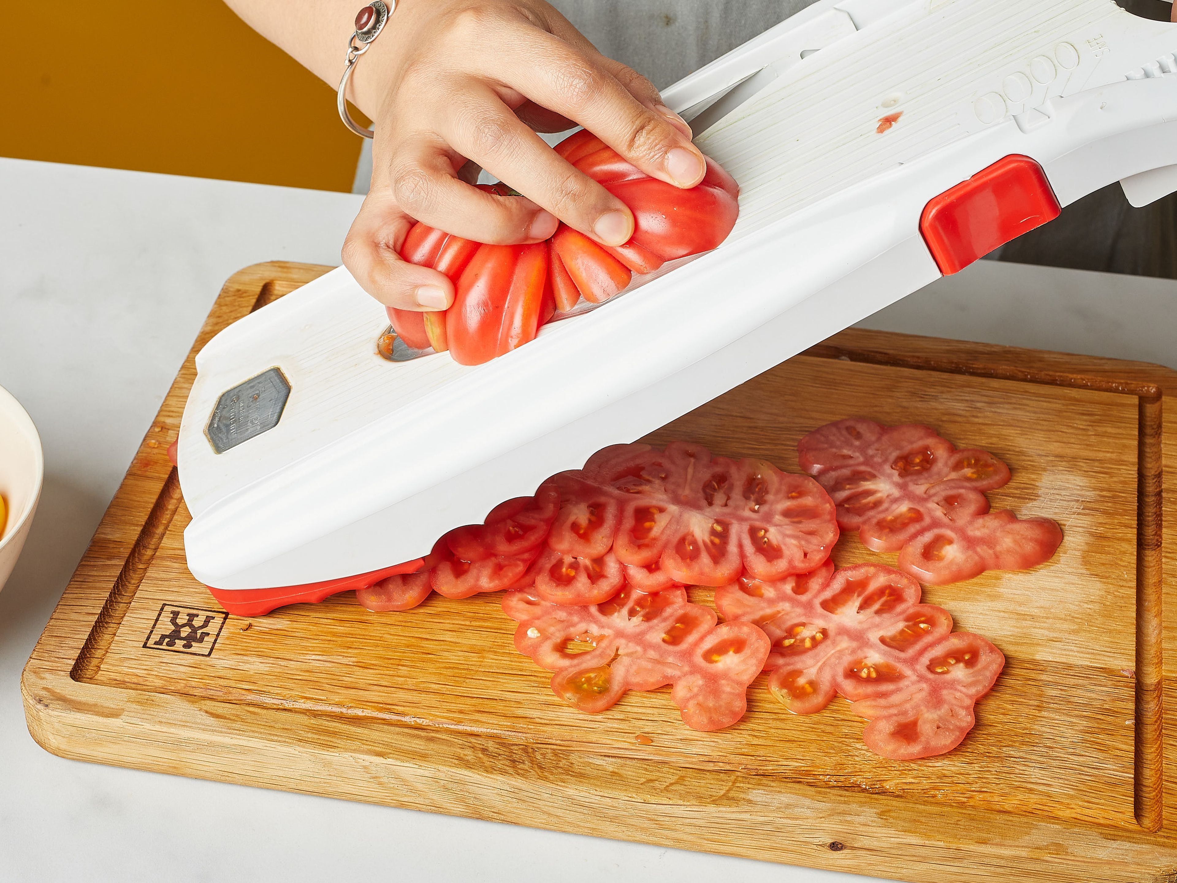 Den Ofen auf 200° vorheizen. Knoblauch fein hacken oder reiben. Größere Tomaten mit Hilfe eines Gemüsehobels, falls du einen hast, in sehr dünne Scheiben schneiden. Cherrytomaten halbieren. In eine Auflaufform geben, salzen und ca. 10 min. stehen lassen, damit die Flüssigkeit etwas austritt.